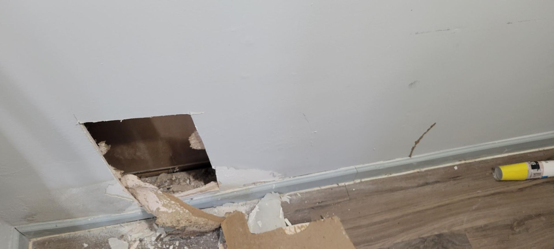 Hole in ceiling exposing interior, debris on floor.