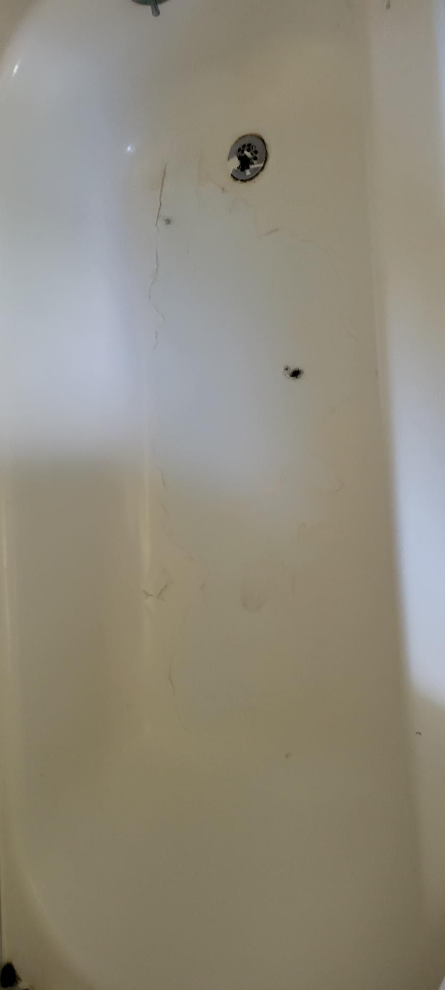 White bathtub with a drain and some dark spots.