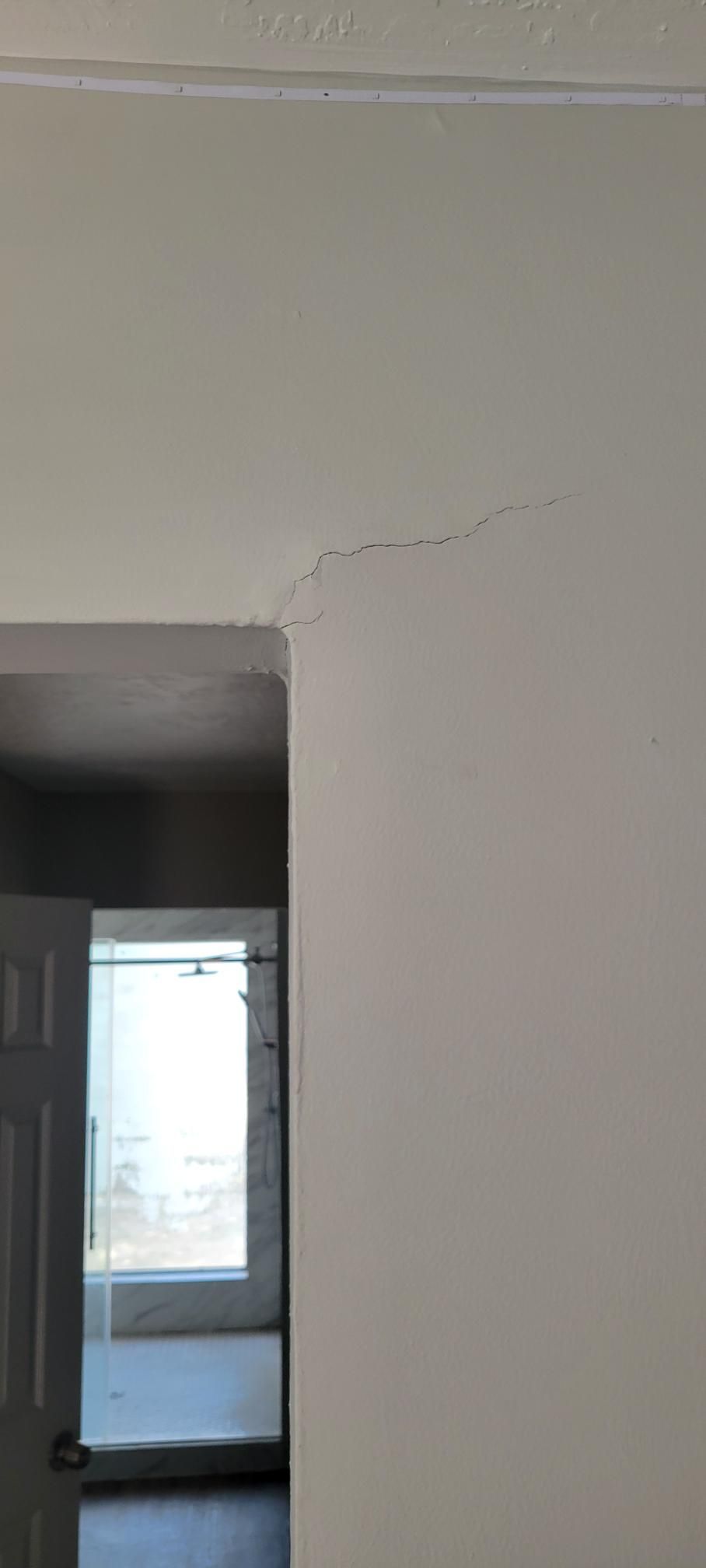 White wall with a crack near the doorway. Another room is visible.