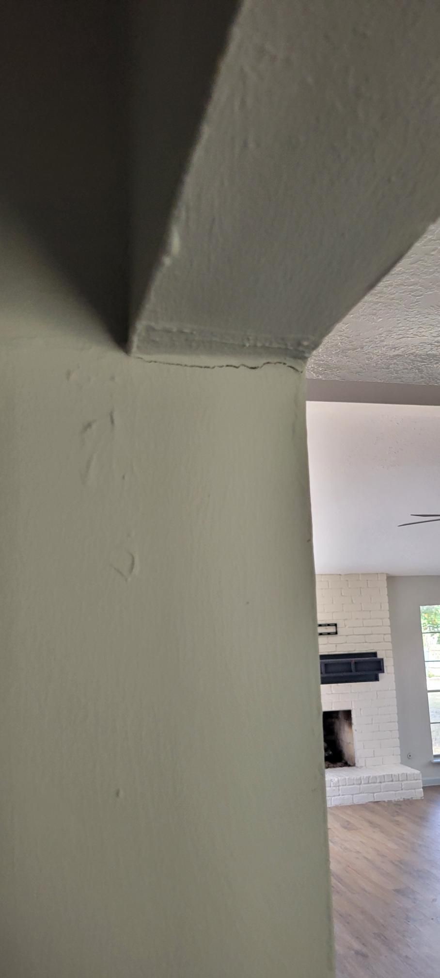 Interior view of a doorway arch and wall painted a light beige color. The wall has some texture.