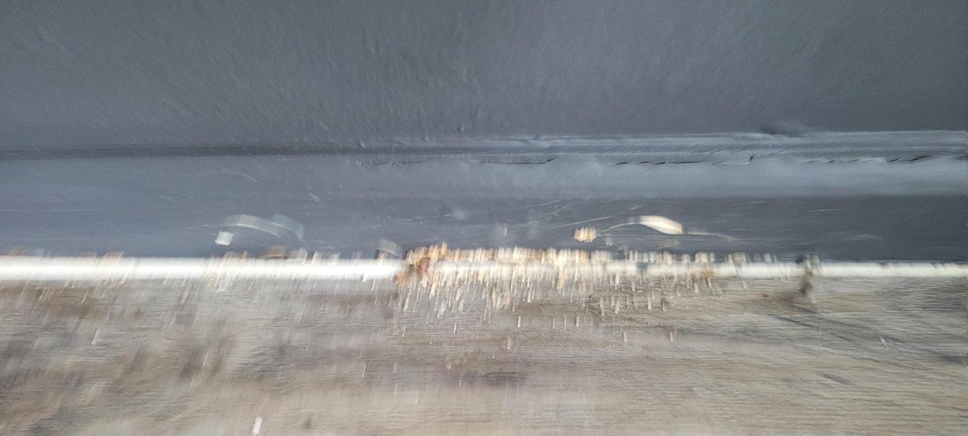 Close-up of a dark grey wall with white debris on the bottom surface.