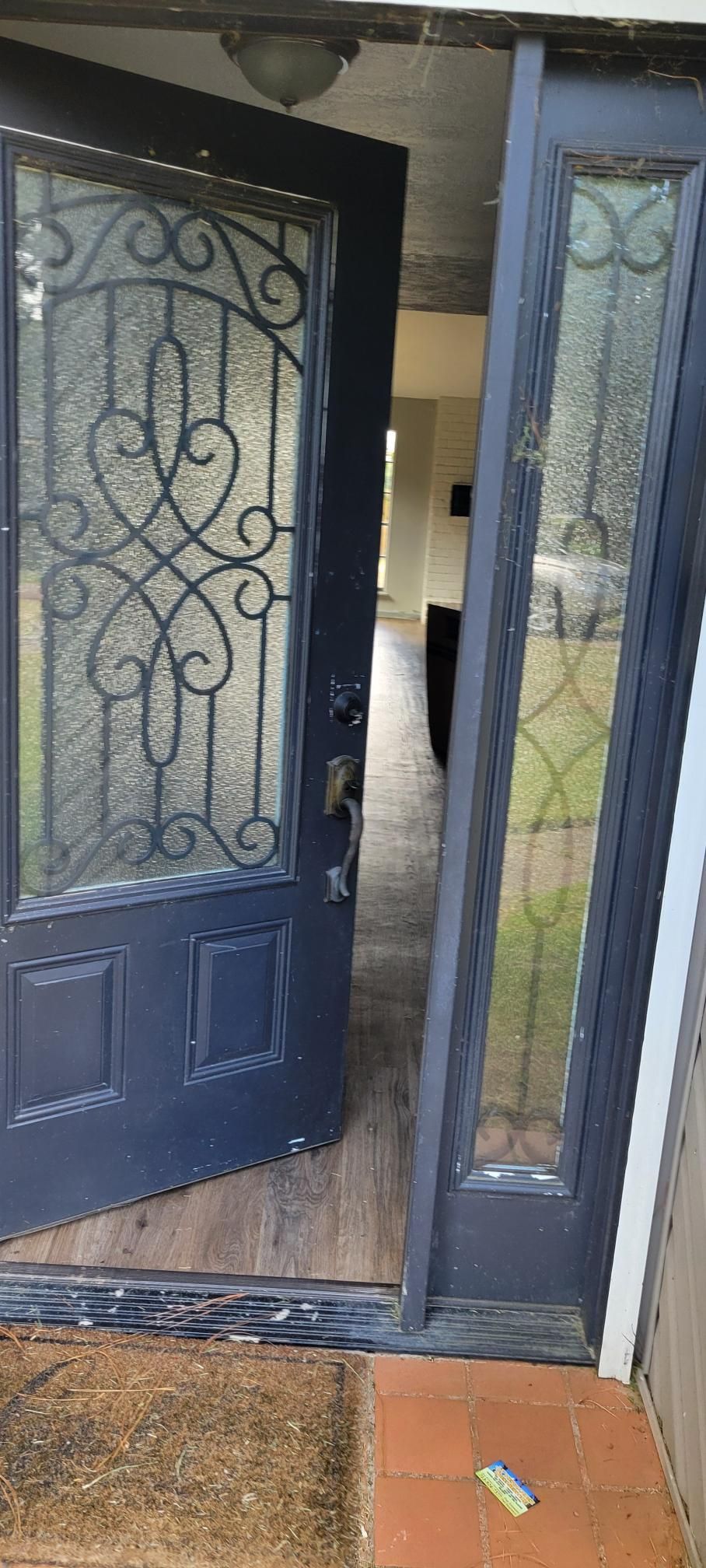 Open black door with decorative glass, revealing a hallway.  A sidelight window is open next to the door.