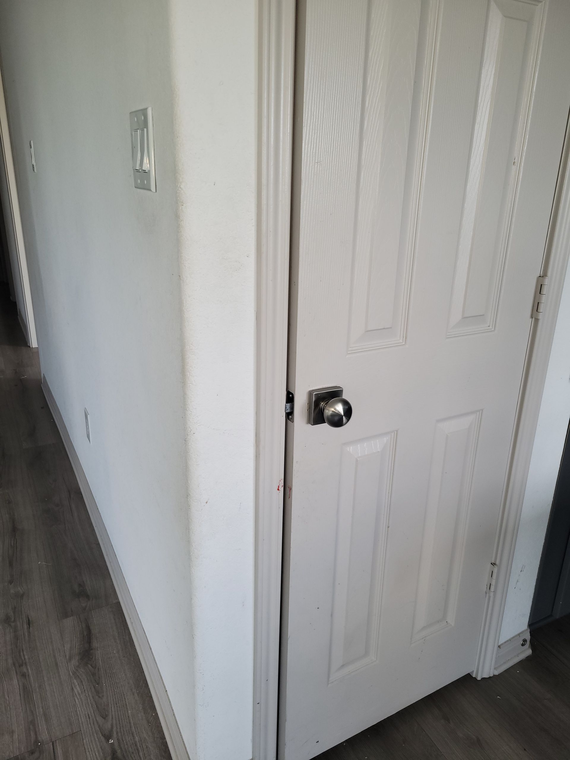 White door ajar in white doorway, light switch visible on wall.