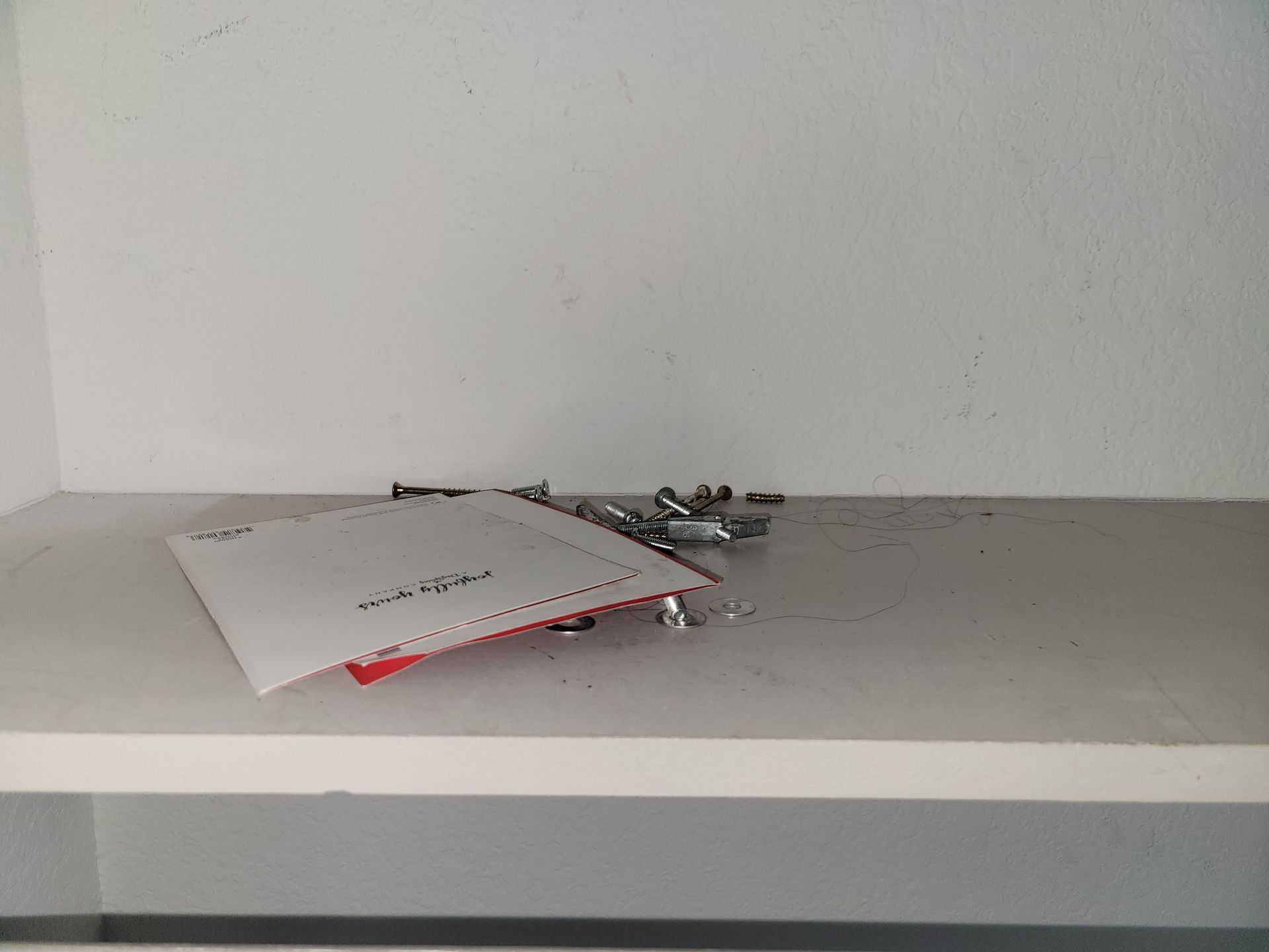 White shelf with small hardware and a red-edged paper.