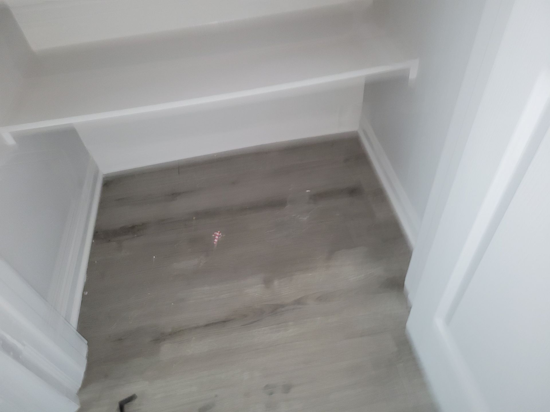 Empty closet with gray flooring, white walls, shelves, and trim.