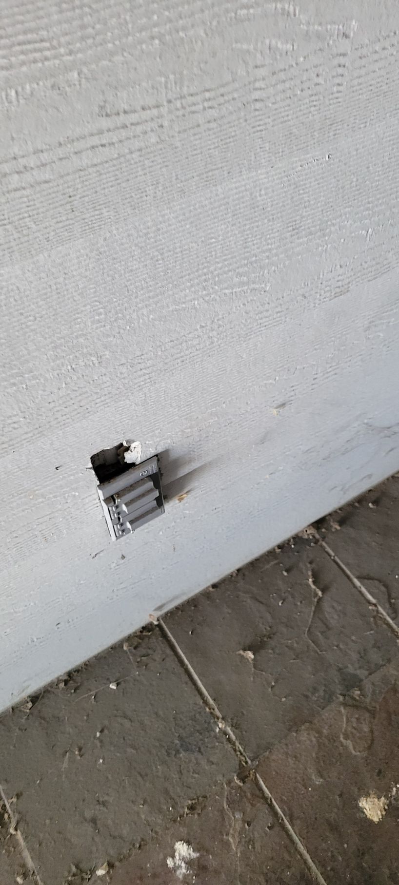Small bundle of silver tubes on a white surface, with a section of dirty, cracked flooring in the foreground.