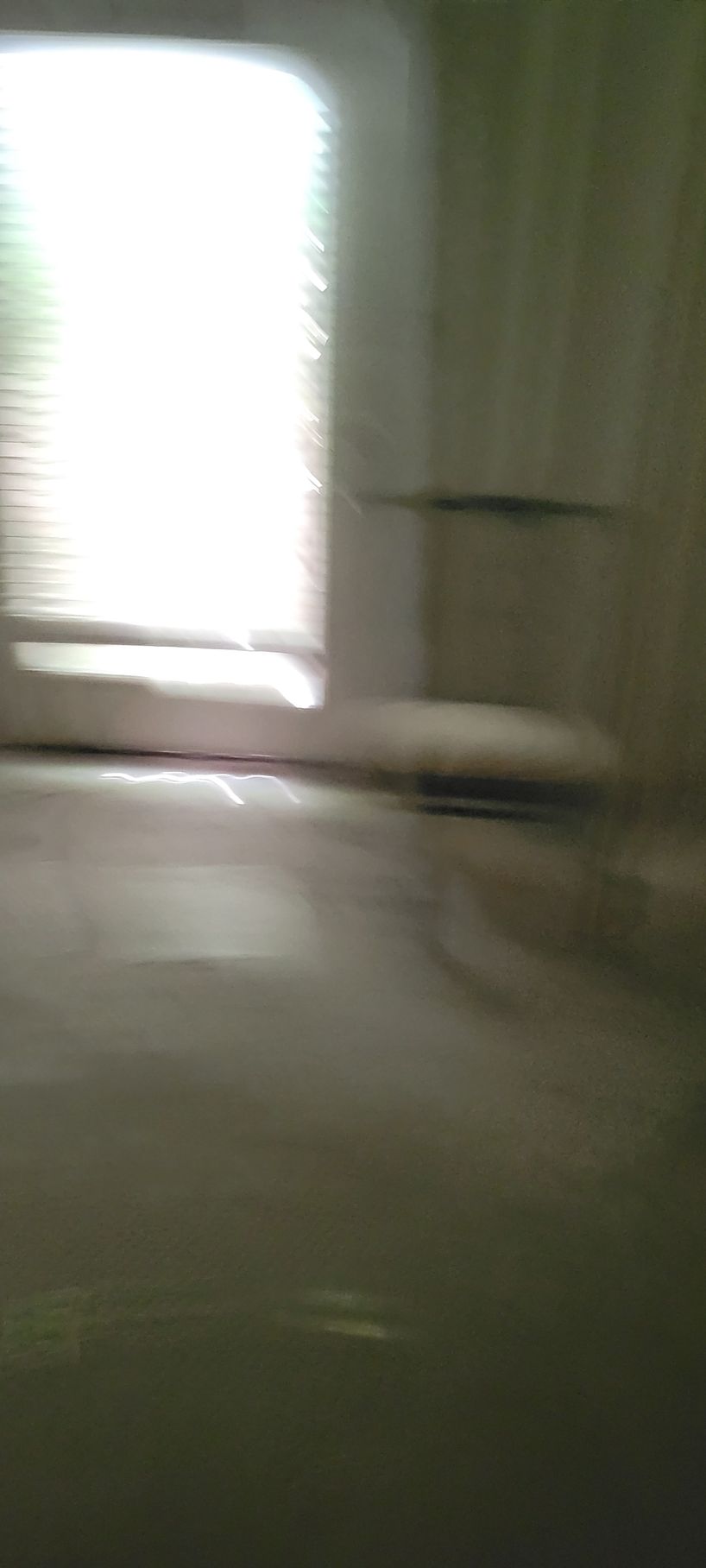 Blurred view of a bright window with blinds and a simple interior.