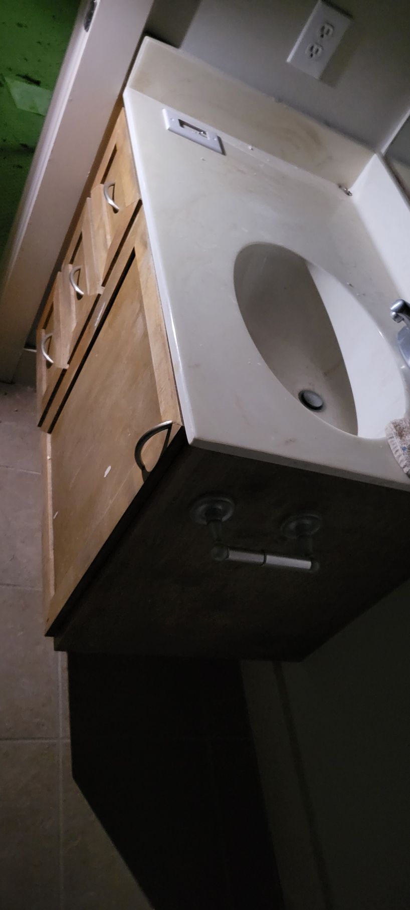 A bathroom vanity with a white countertop and a light-colored wood cabinet, and a single sink.