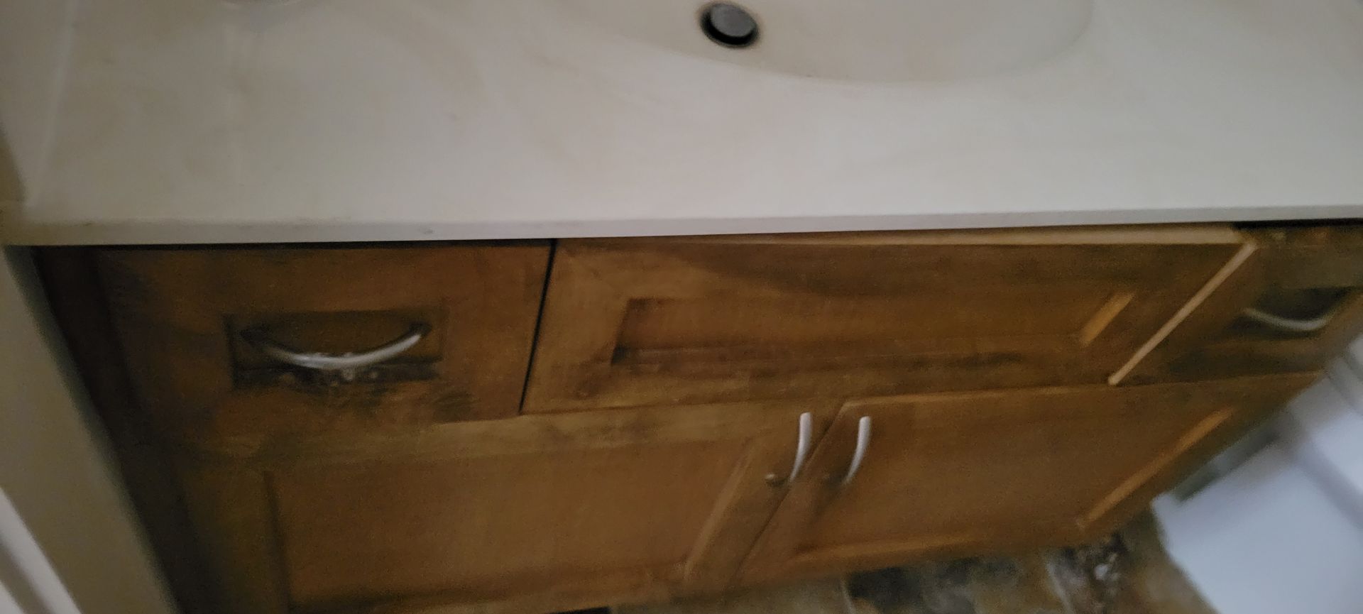 Bathroom vanity with wood cabinets and a white countertop.
