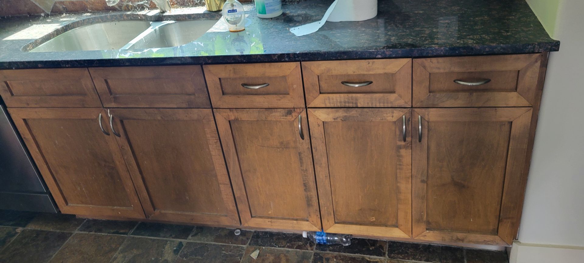 Kitchen cabinets with brown wooden doors and black countertop. A sink is visible.