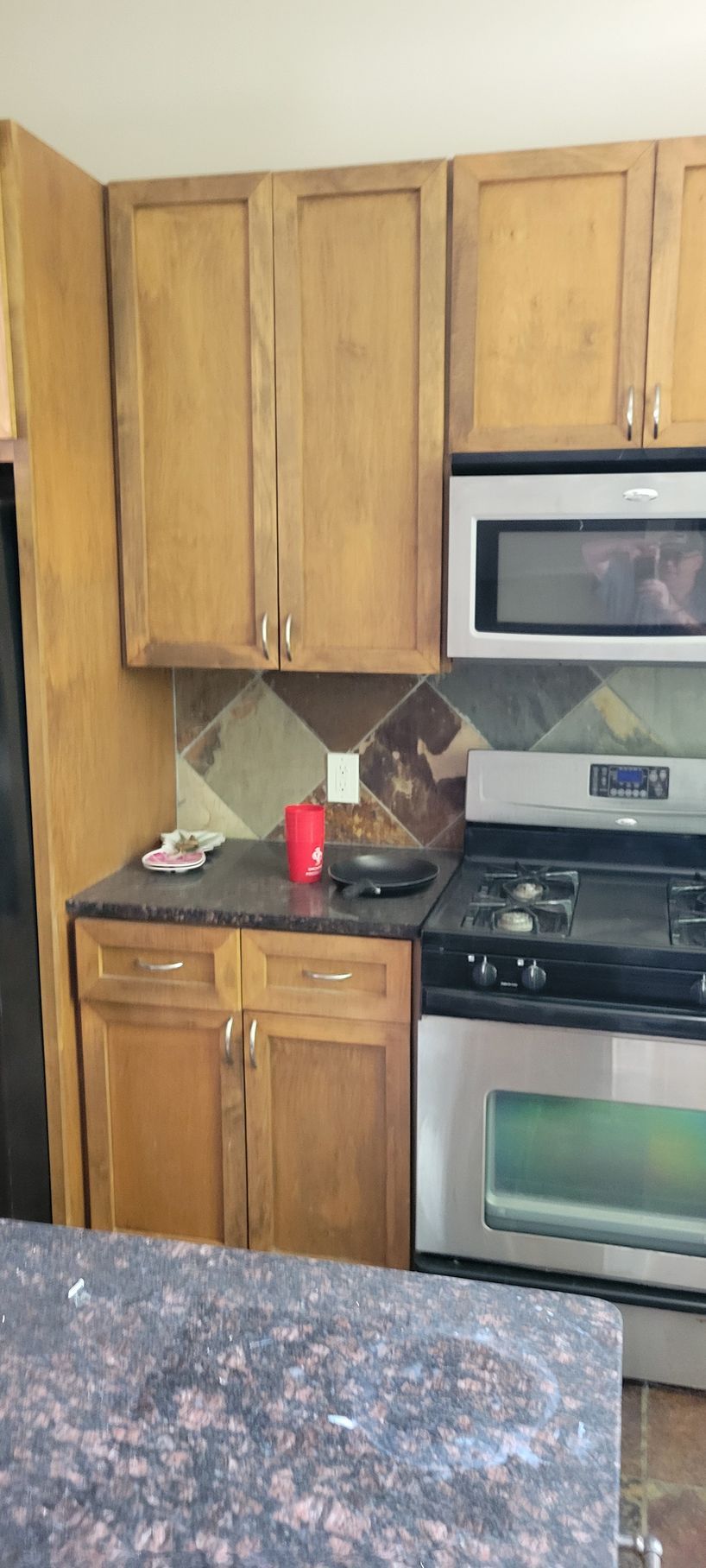 A kitchen with wooden cabinets, stainless steel appliances, and a tiled backsplash.
