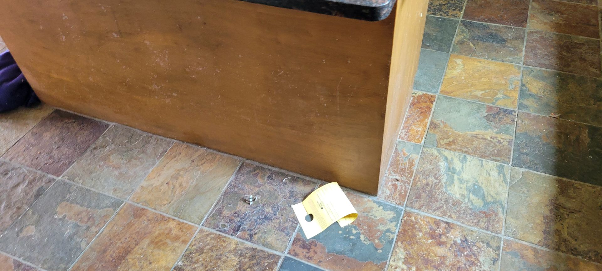 Brown cabinet and stone-like floor with a yellow paper.
