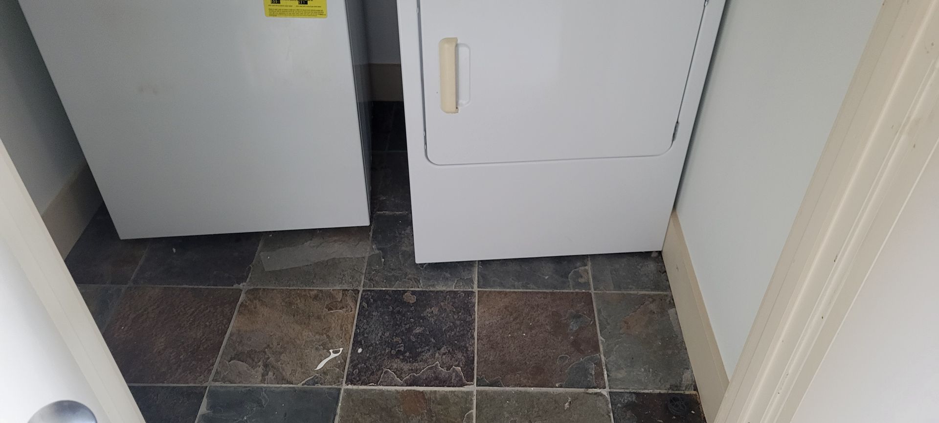 Laundry room with white appliances and slate tile flooring.