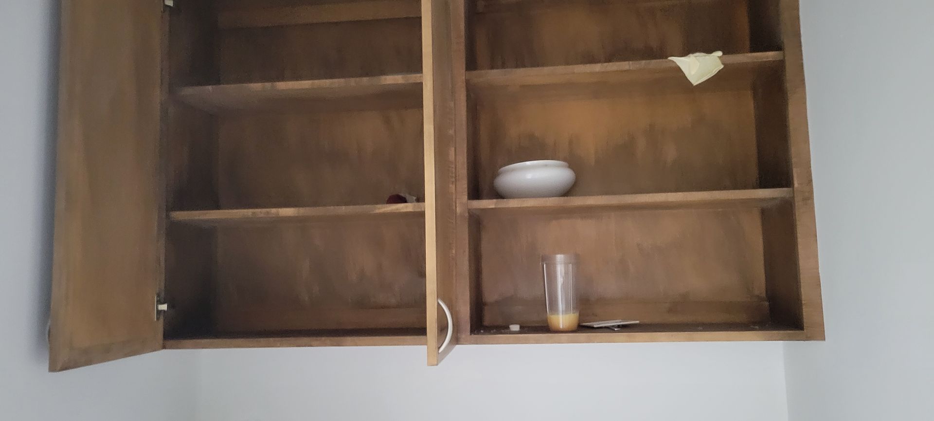 Wooden cabinet with open doors, partially empty. Items on shelves.