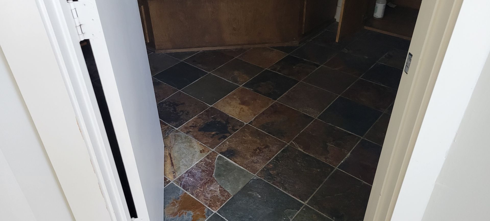 Looking into a bathroom with slate tile flooring. The doorway is framed in white.