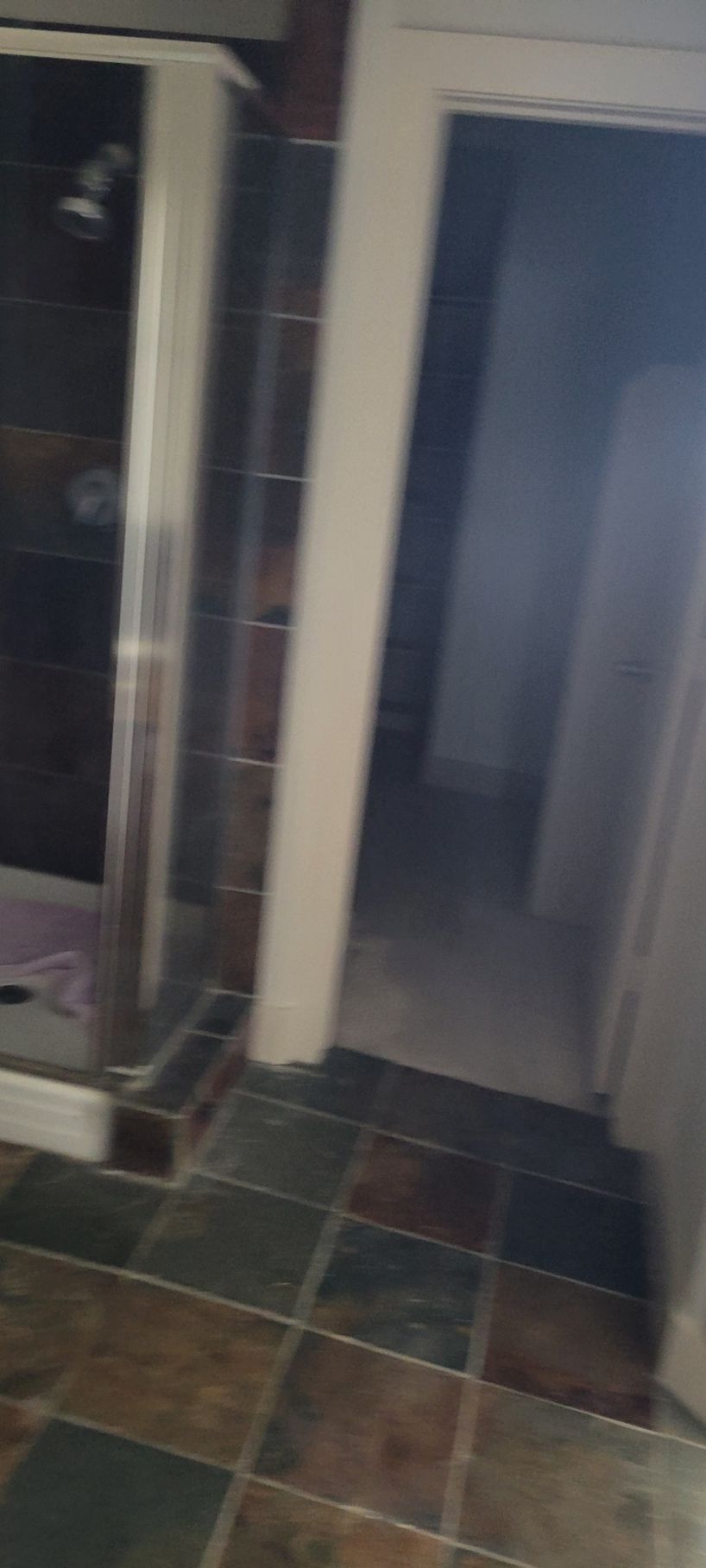 Bathroom with a shower stall, tile flooring, and an open doorway.