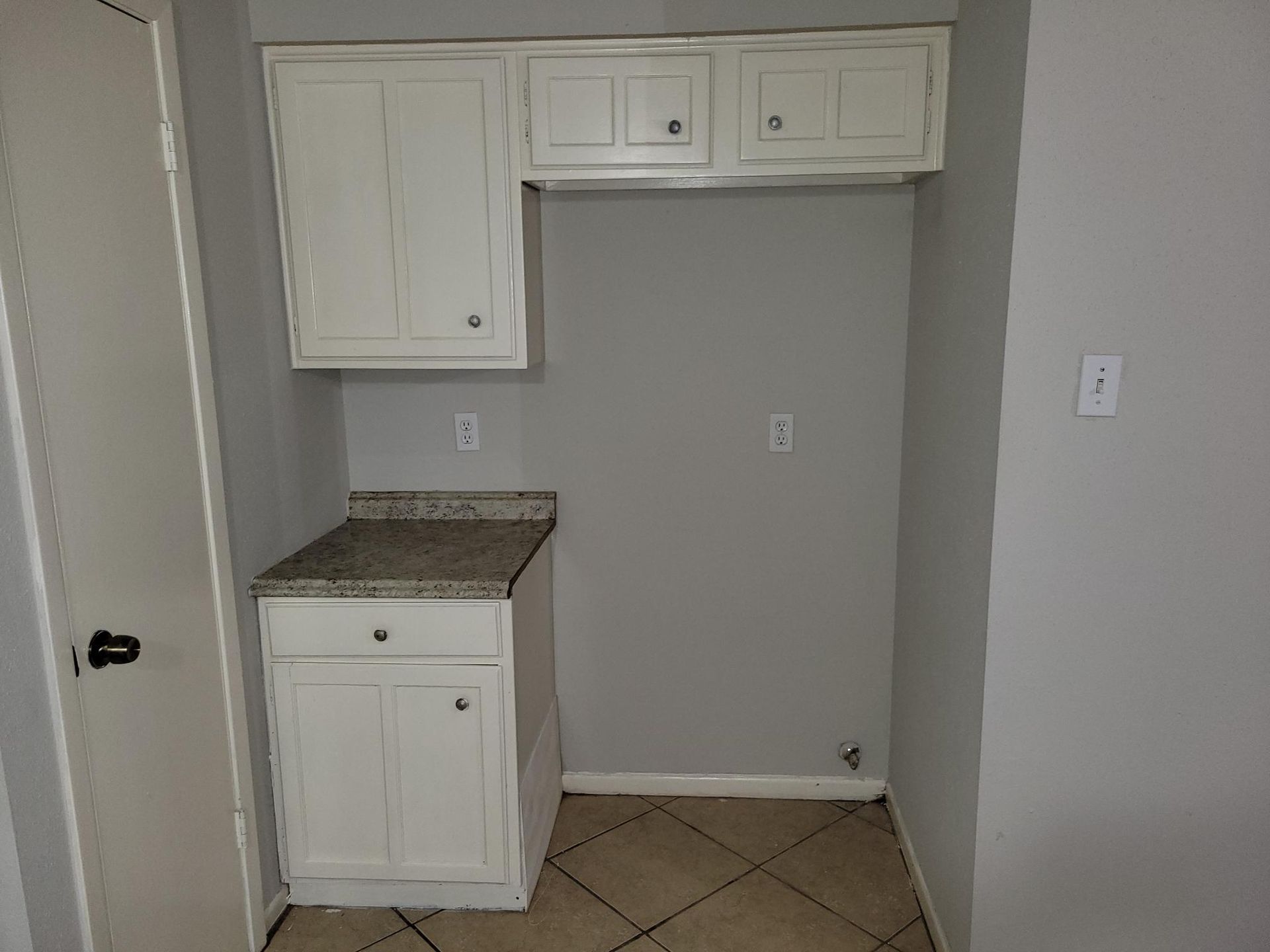 Small kitchen nook with white cabinets, gray walls, and granite countertop.