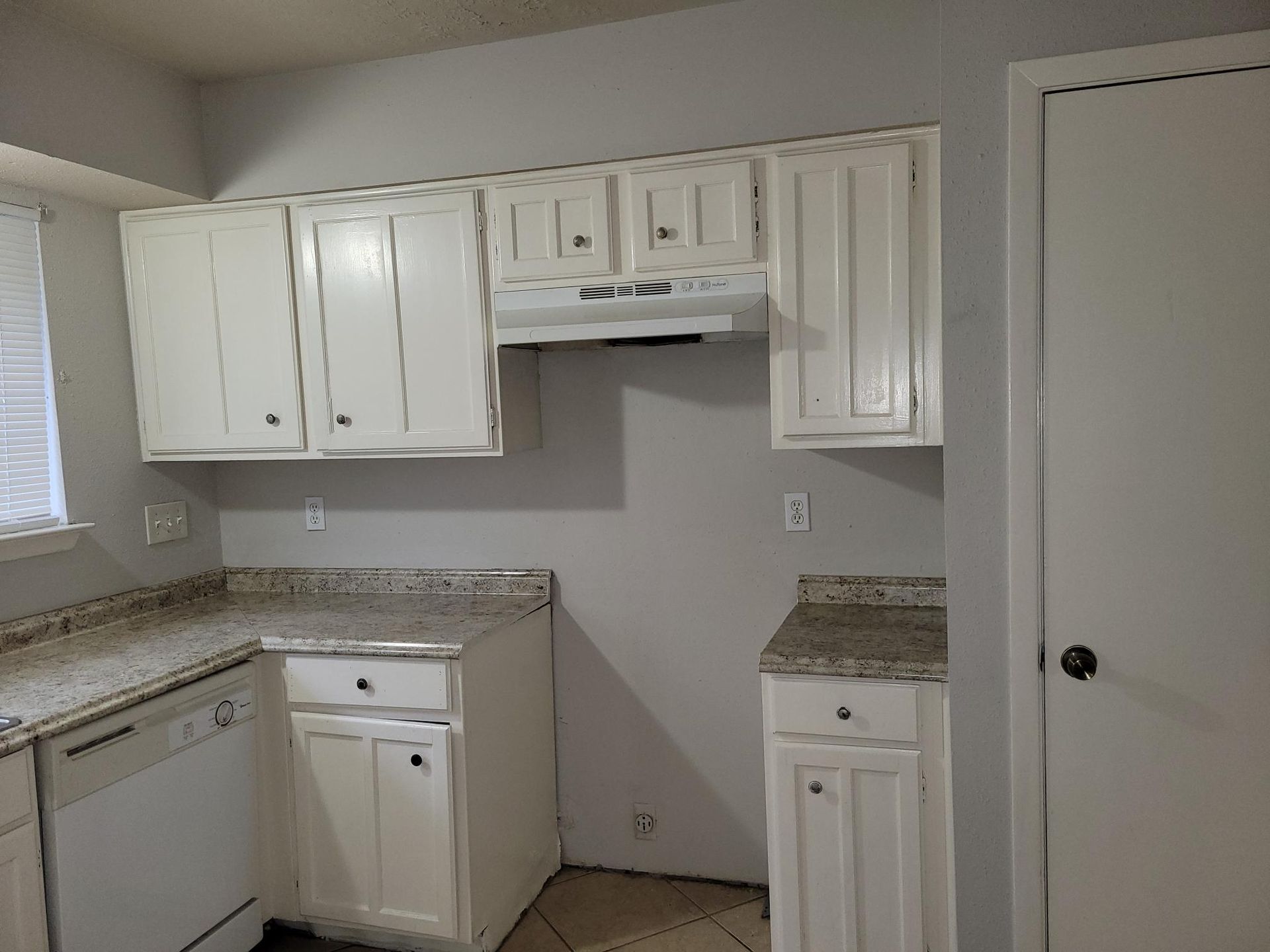 White kitchen cabinets with granite countertops.