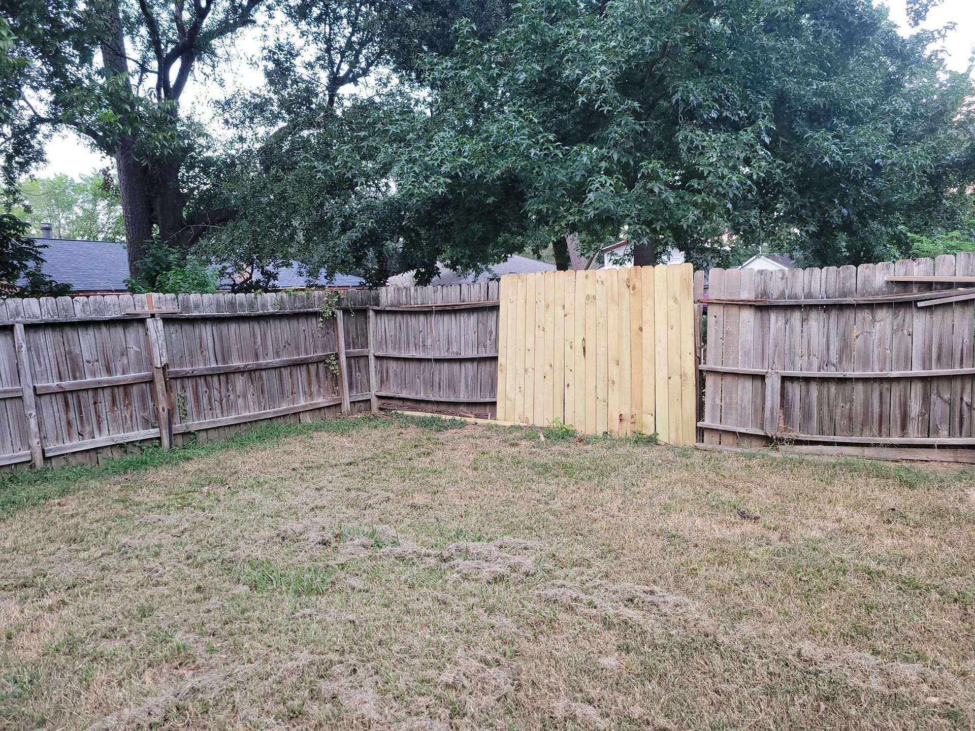 Backyard with brown wooden fences and a newer light-colored wooden panel.