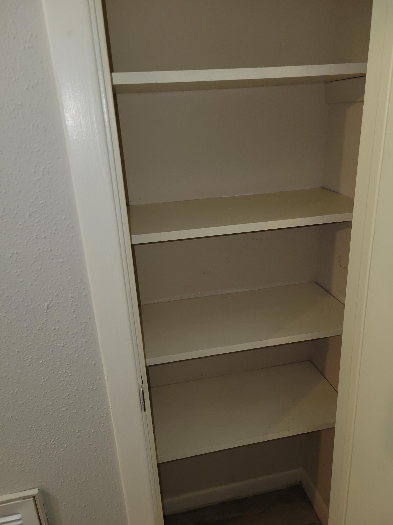 Empty white shelves inside a closet.