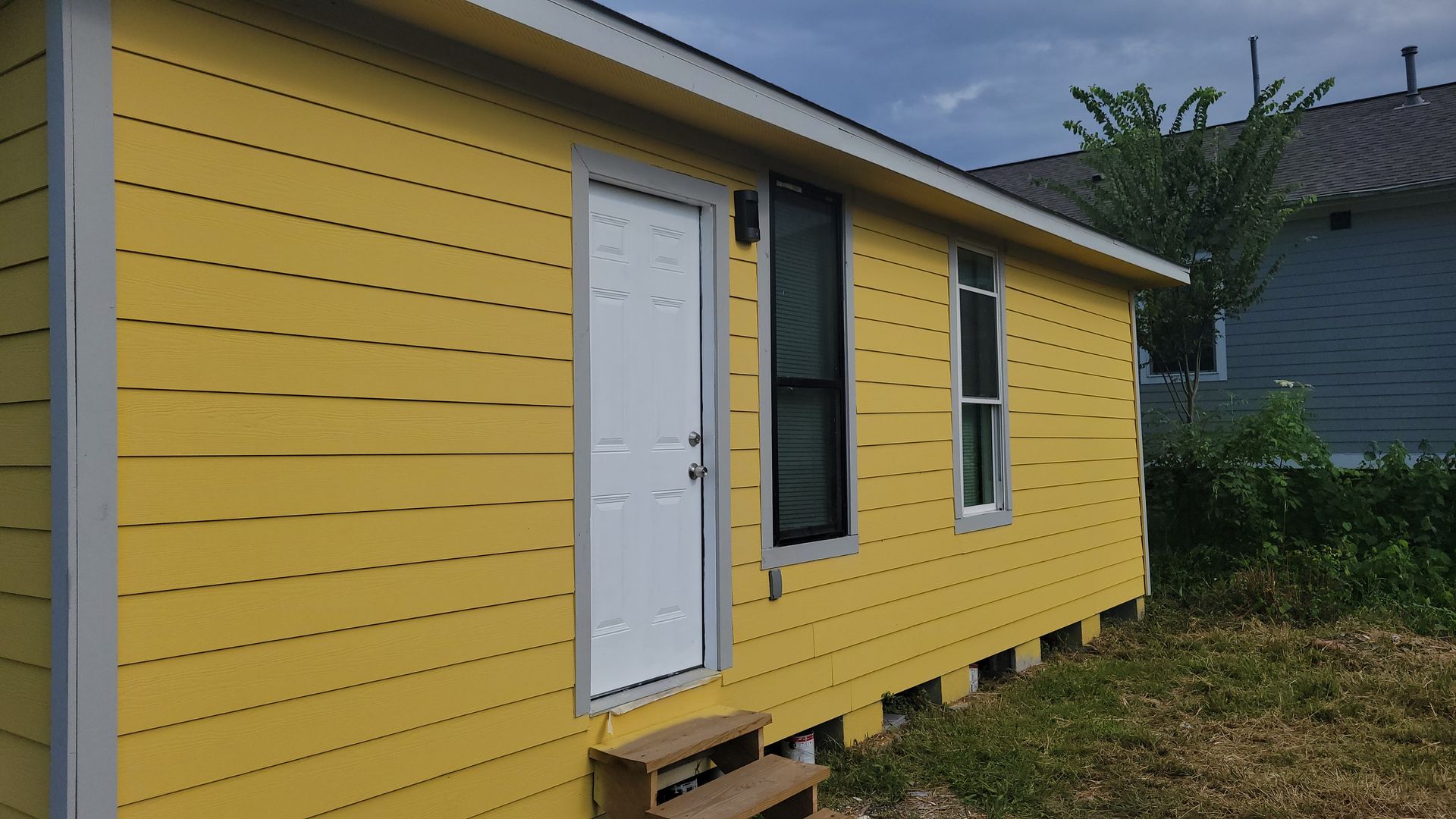 Yellow building with white door and windows, wooden steps.