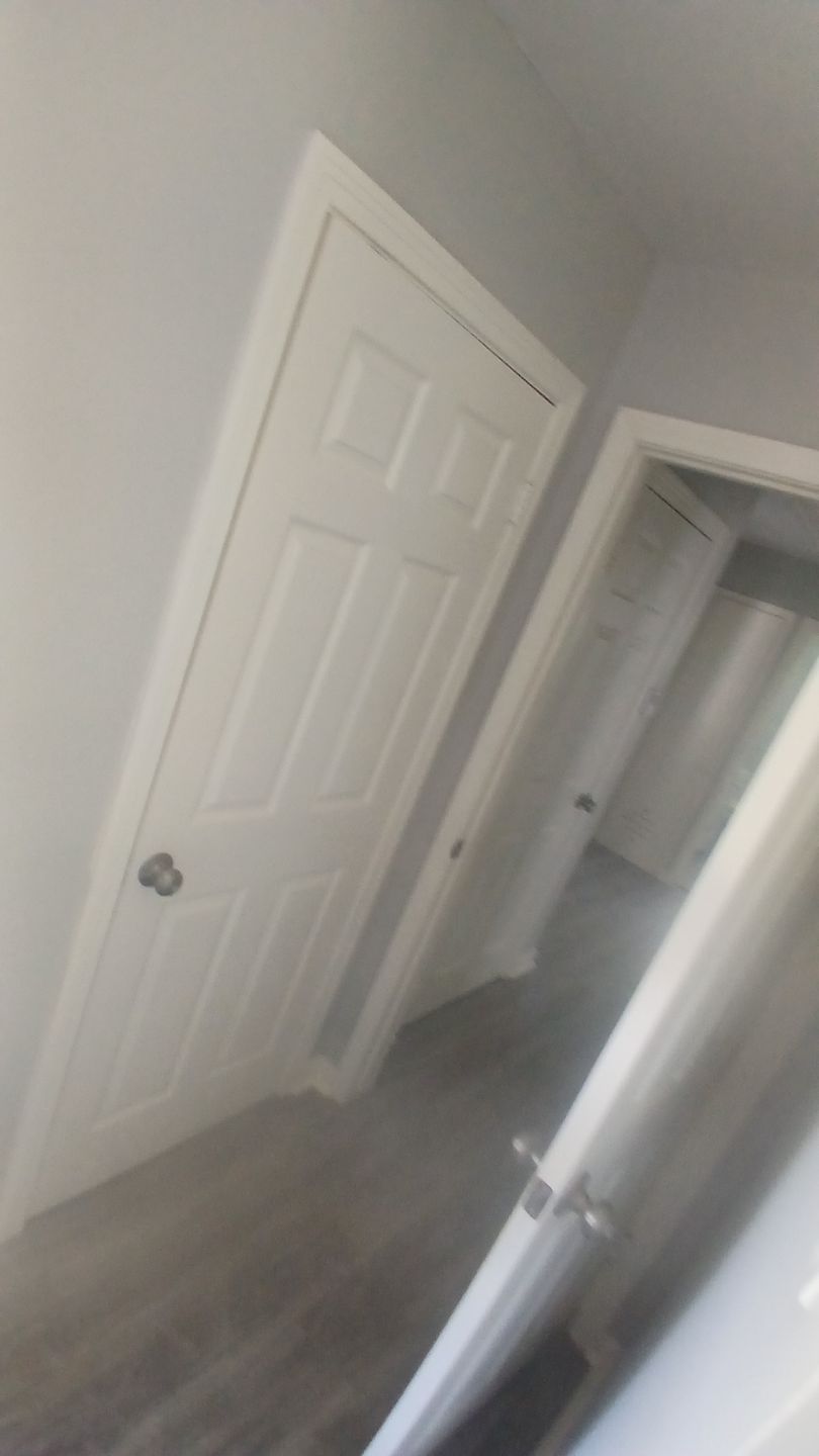 White six-panel door in a gray hallway, a door frame visible on the right.