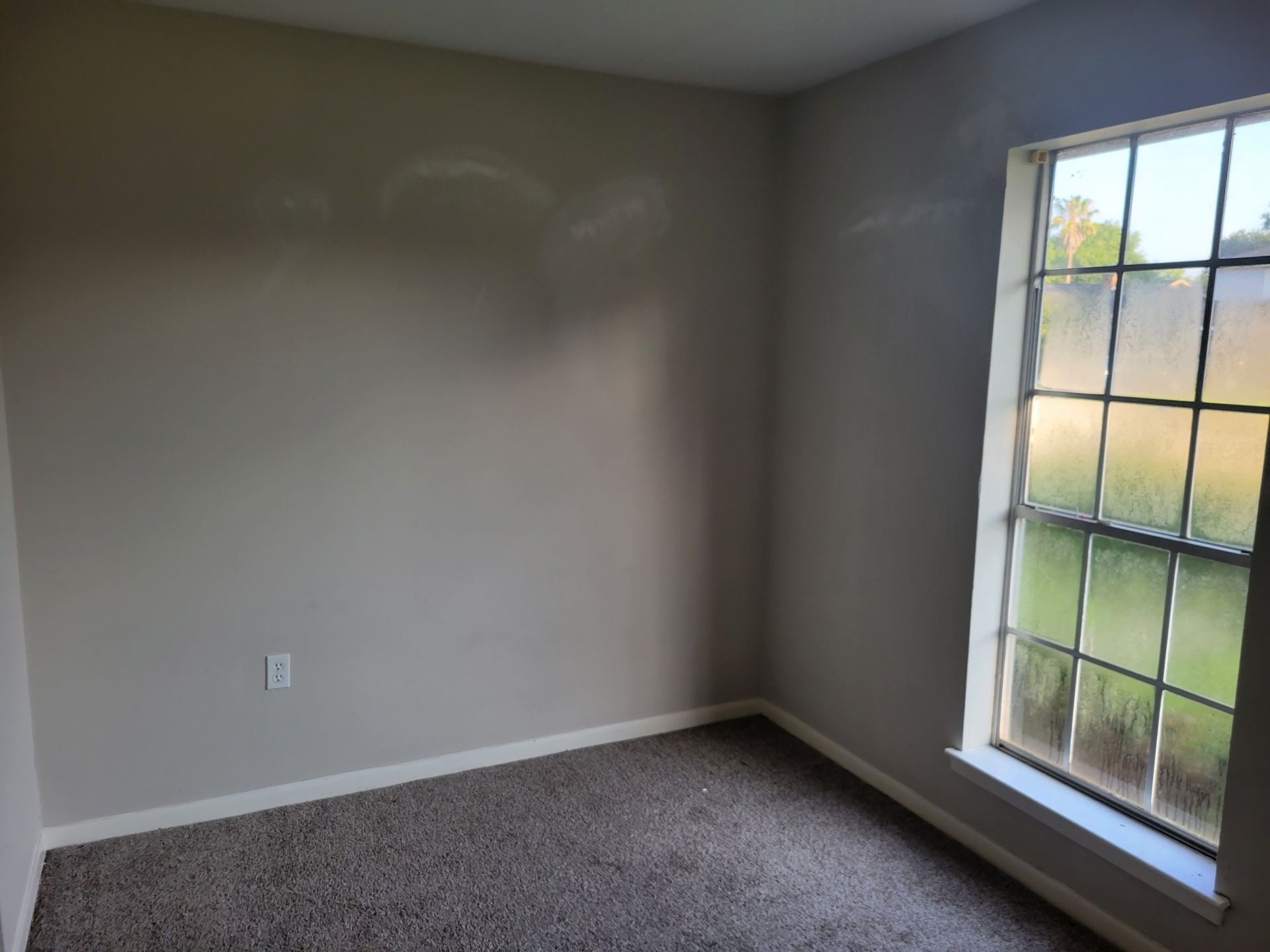 Empty room with gray walls, window, and carpet.
