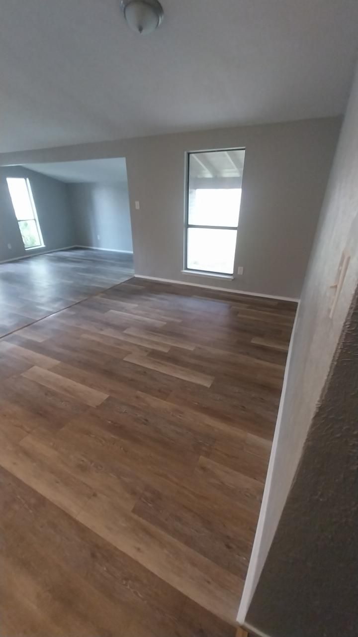 Interior view of a room with wood-look flooring, gray walls, and a window.