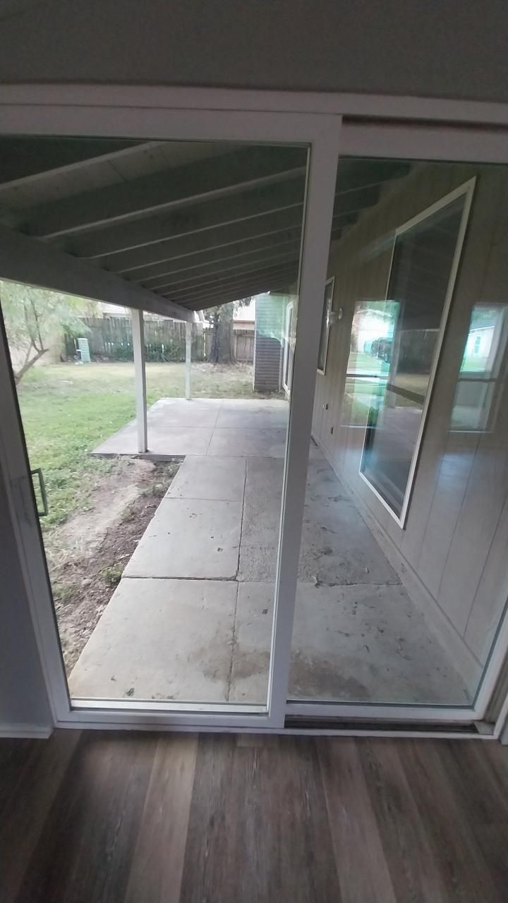 Sliding glass door opens to a covered patio with a concrete walkway and yard.