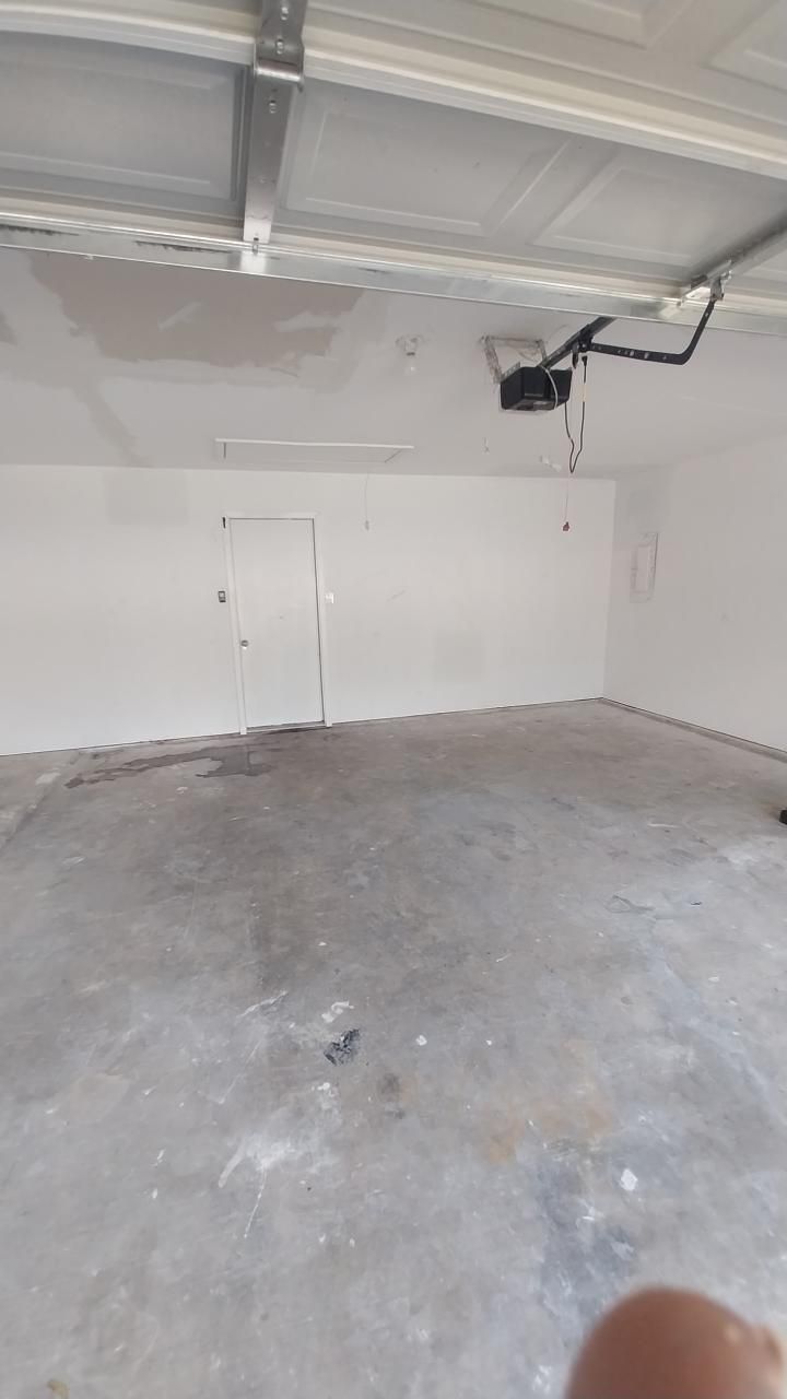 Empty garage interior with white walls, concrete floor, and garage door opener.