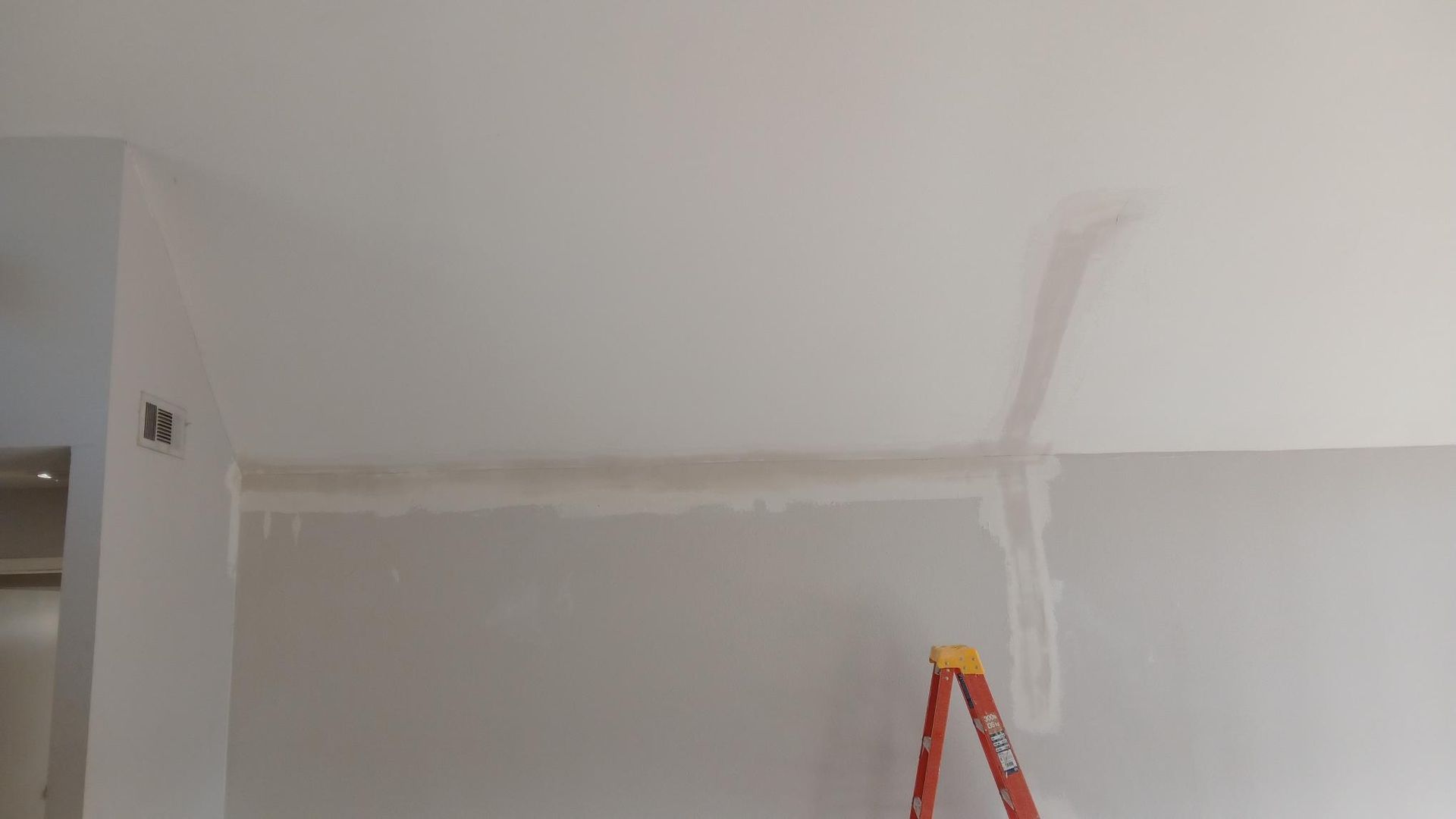 Interior view of a room with a white ceiling and walls, a ladder, and exposed wires.