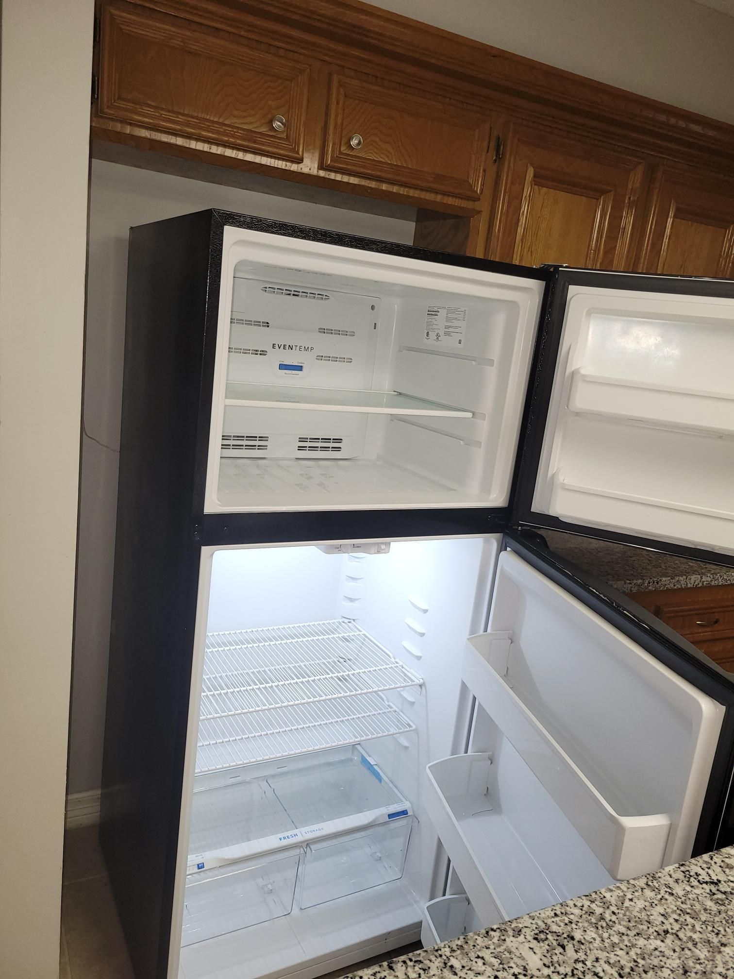 Black refrigerator with open doors, shelves visible, in a kitchen.