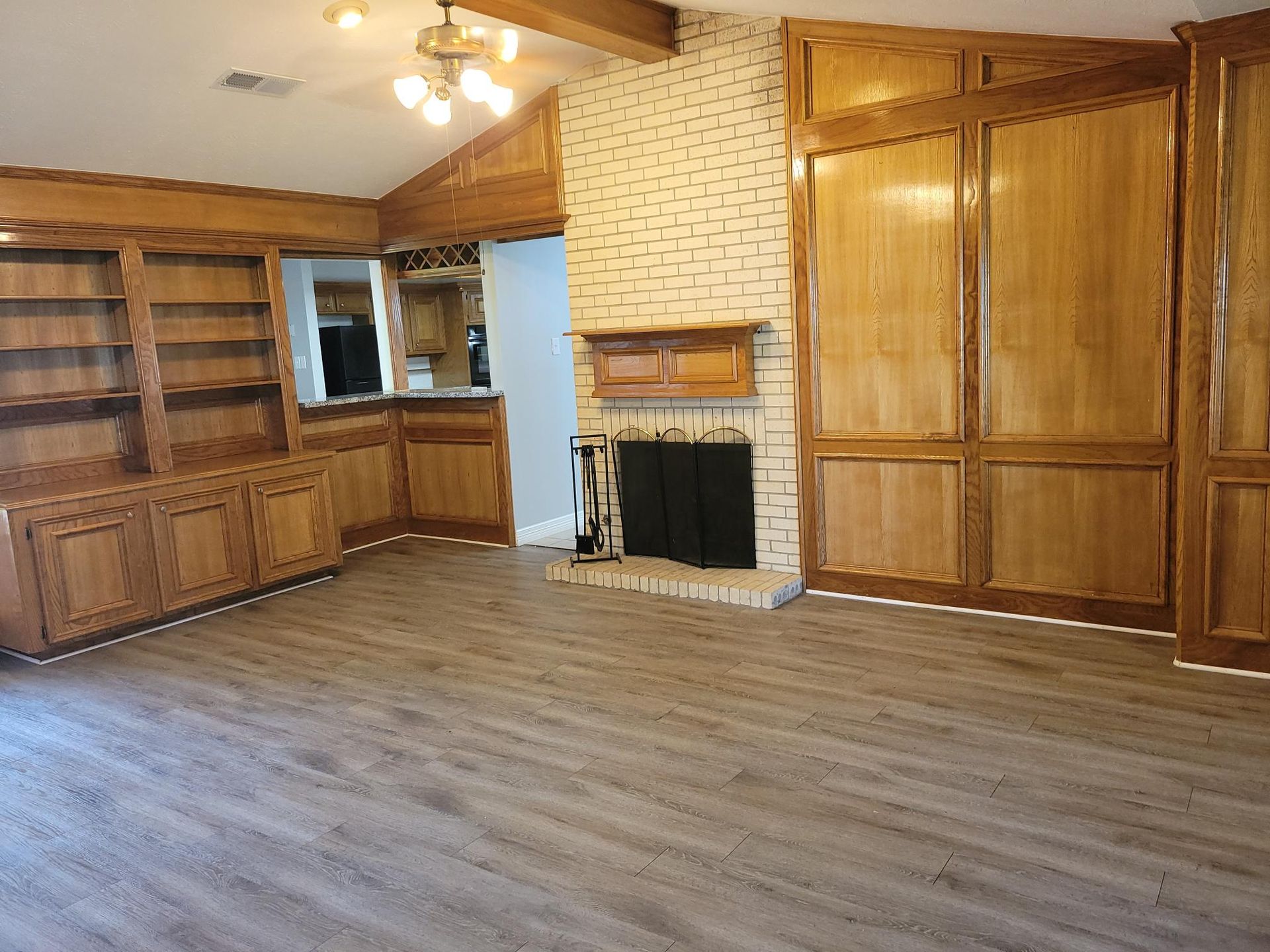 Living room with wood paneling, fireplace, built-in shelves, and gray flooring.