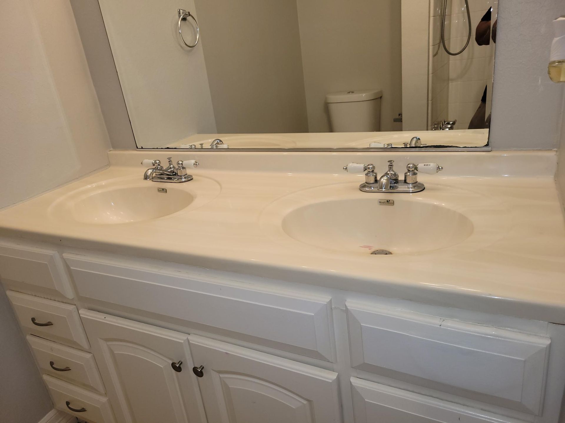 Bathroom vanity with two sinks, white cabinets, and large mirror.