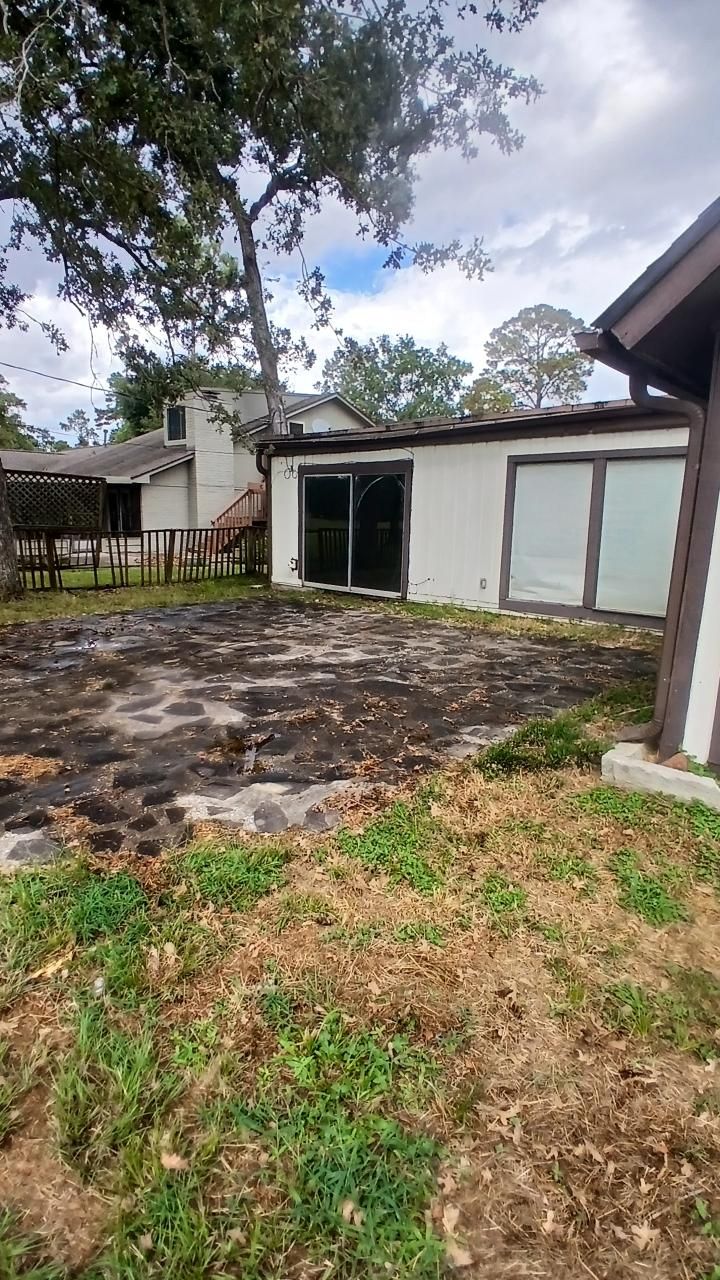 Backyard with dirt patch, white house, sliding glass doors, brown trim, and overcast sky.
