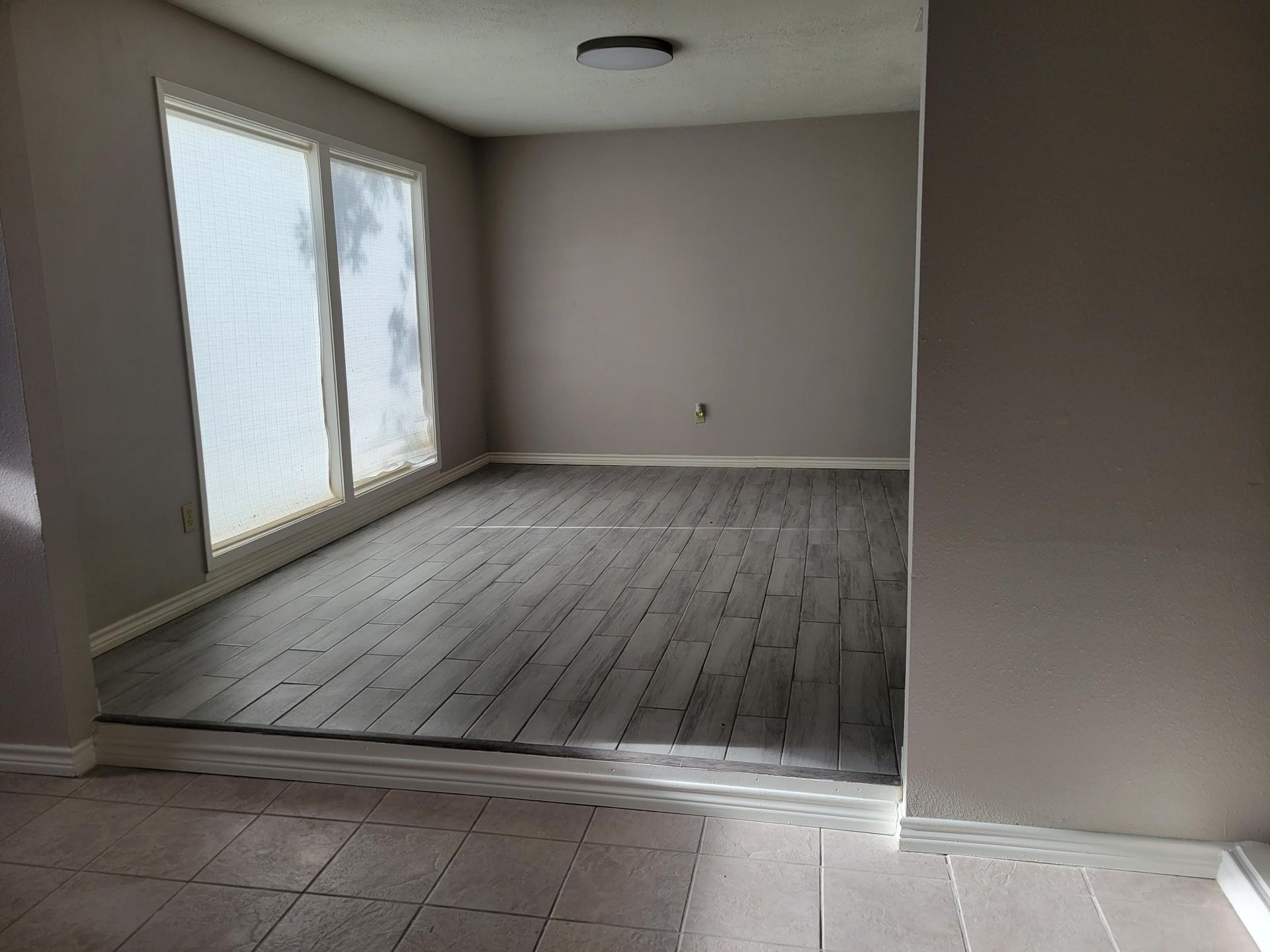 Empty room with gray-painted walls, wood flooring, and large window.
