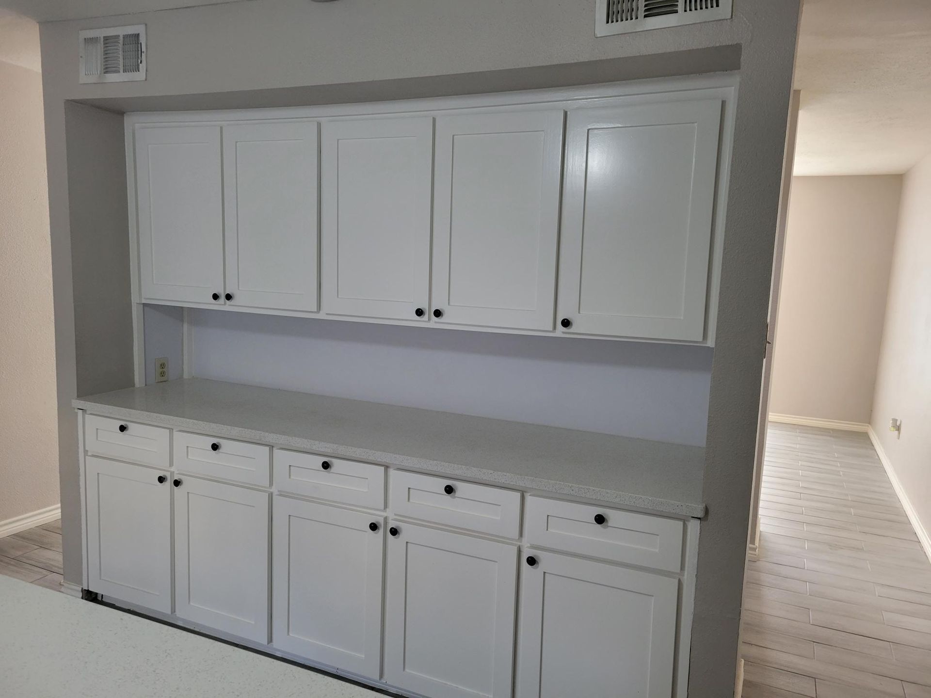Built-in white cabinets with countertop in a room; a hallway visible on the right.