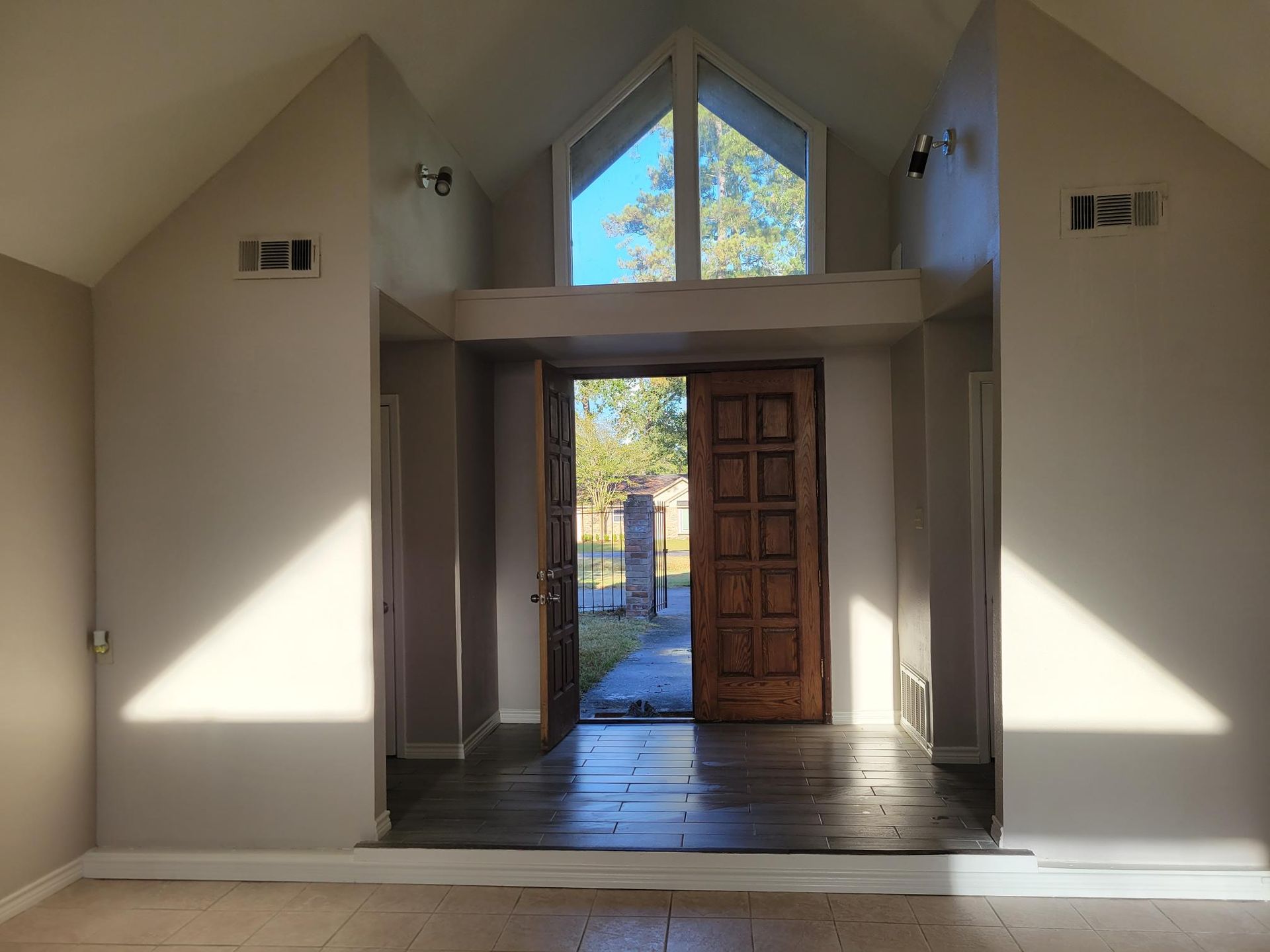 Entryway with open wooden door, large window above, light on walls.