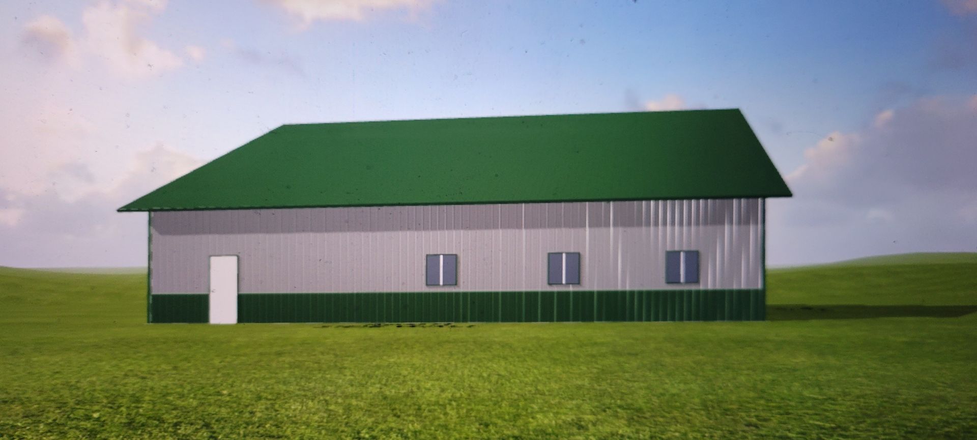 A green-roofed metal barn sits in a grassy field under a cloudy sky.