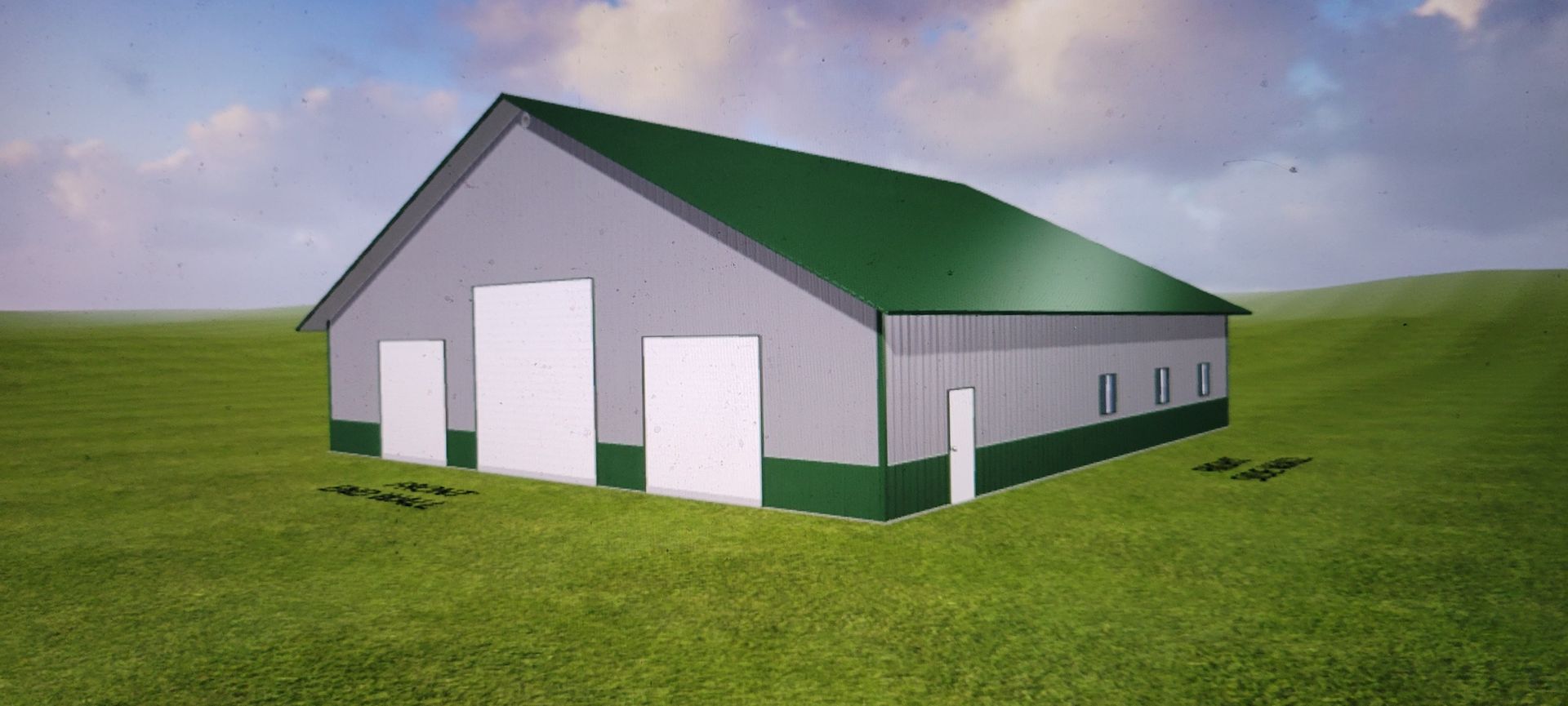 A gray barn with a green roof and trim, standing in a grassy field under a cloudy sky.