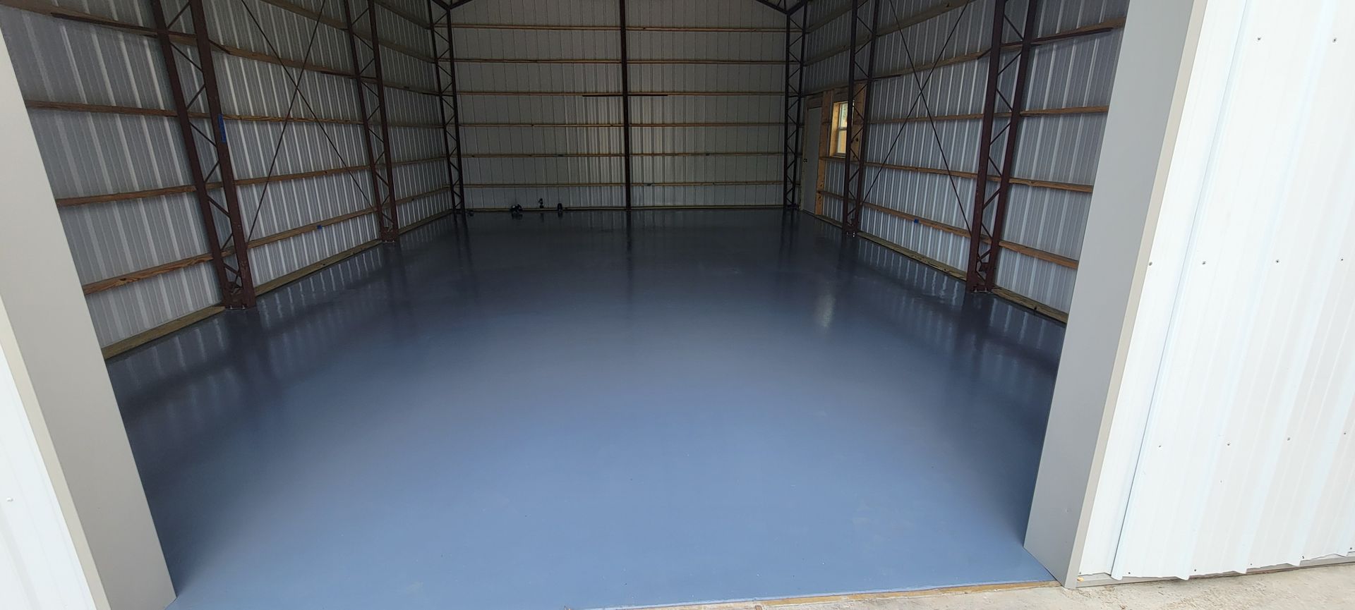Interior of a newly painted, light blue, metal building with shiny floor.