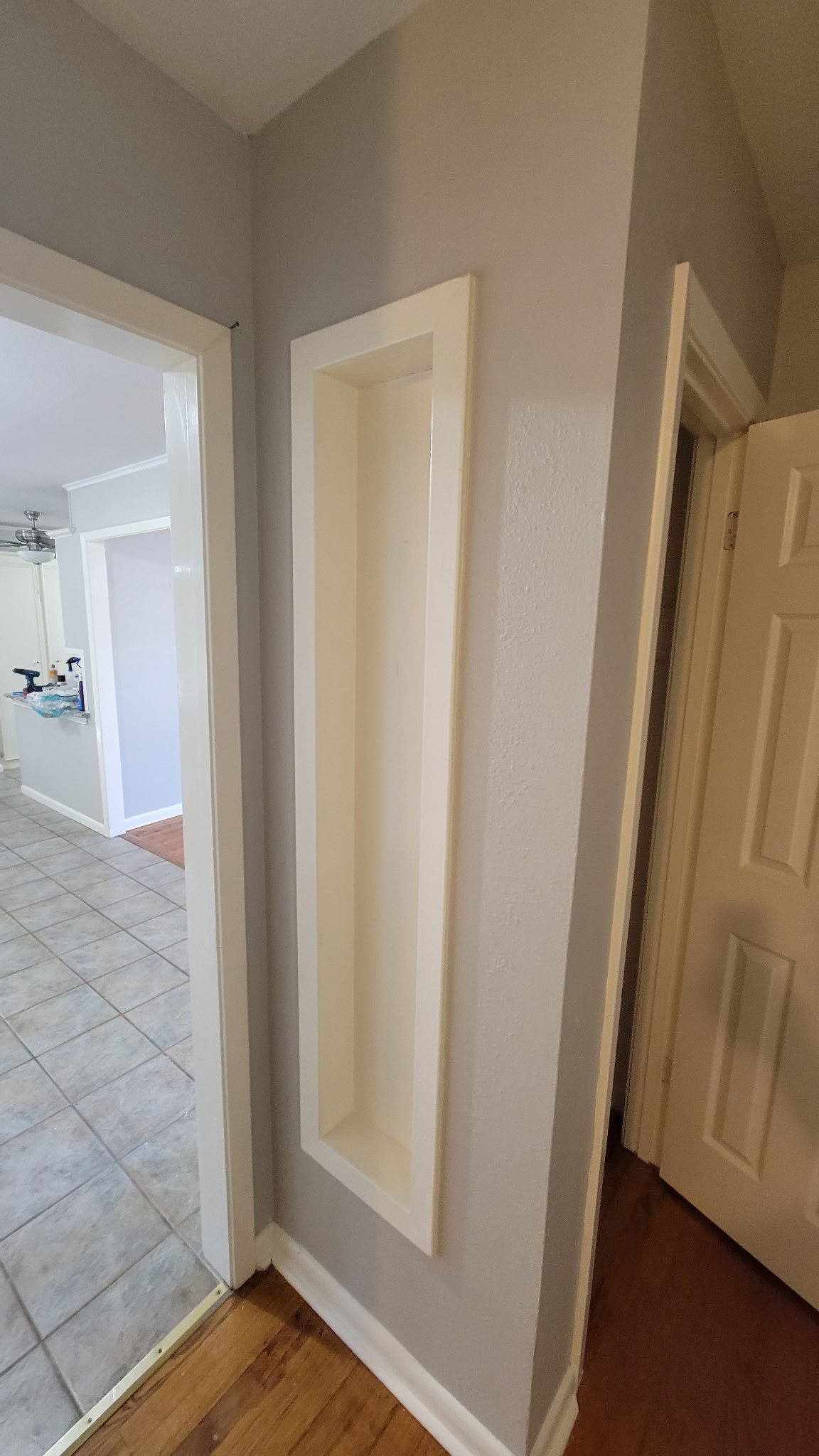 Recessed wall shelf painted white in a gray hallway, near doorways.