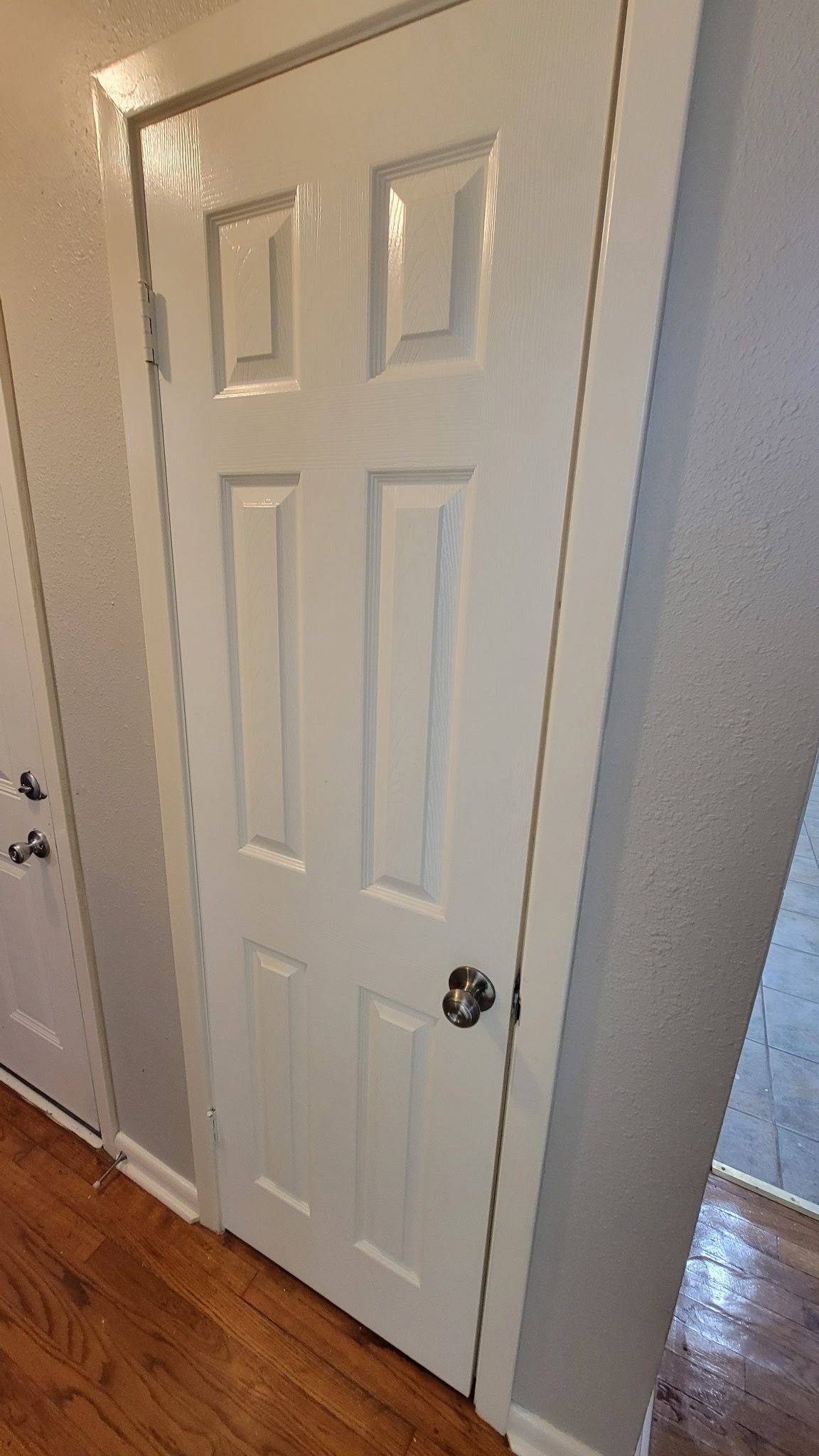 White six-panel door with a silver knob and frame against gray walls, hallway.
