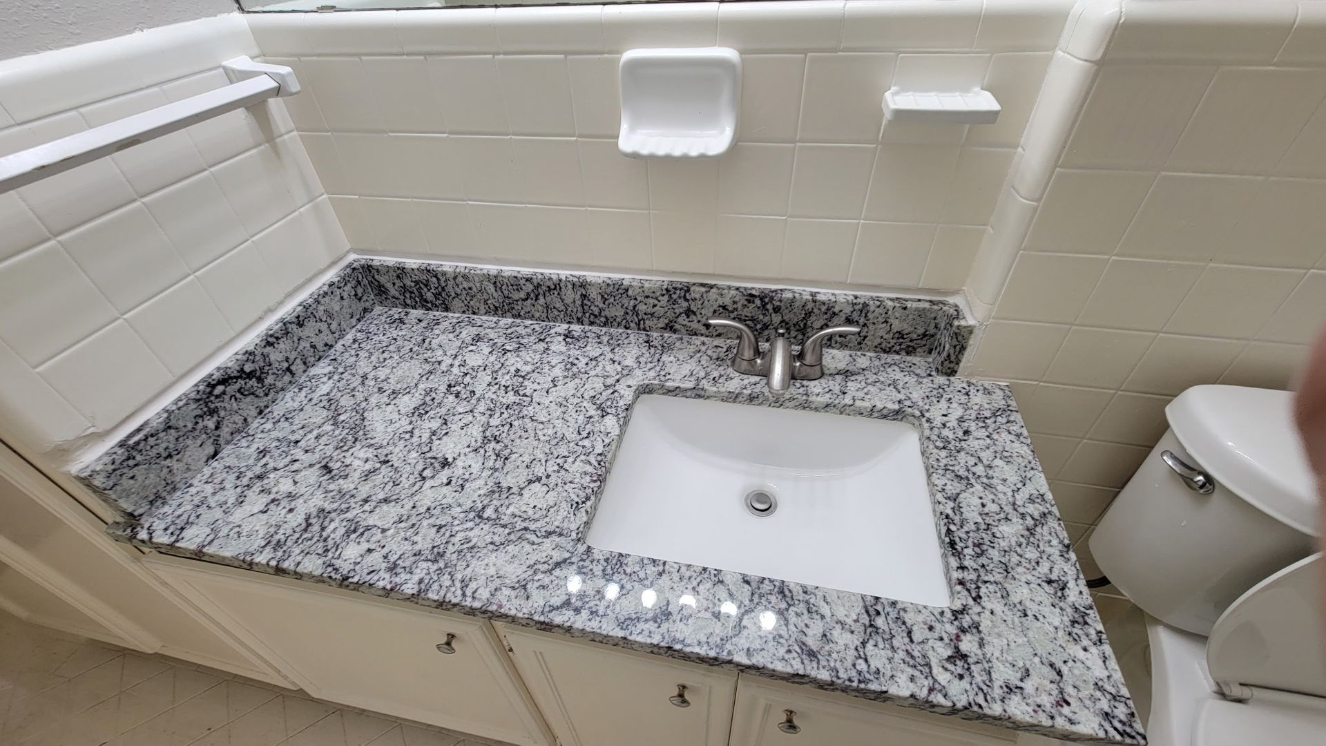 Bathroom vanity with granite countertop, white sink, and toilet.