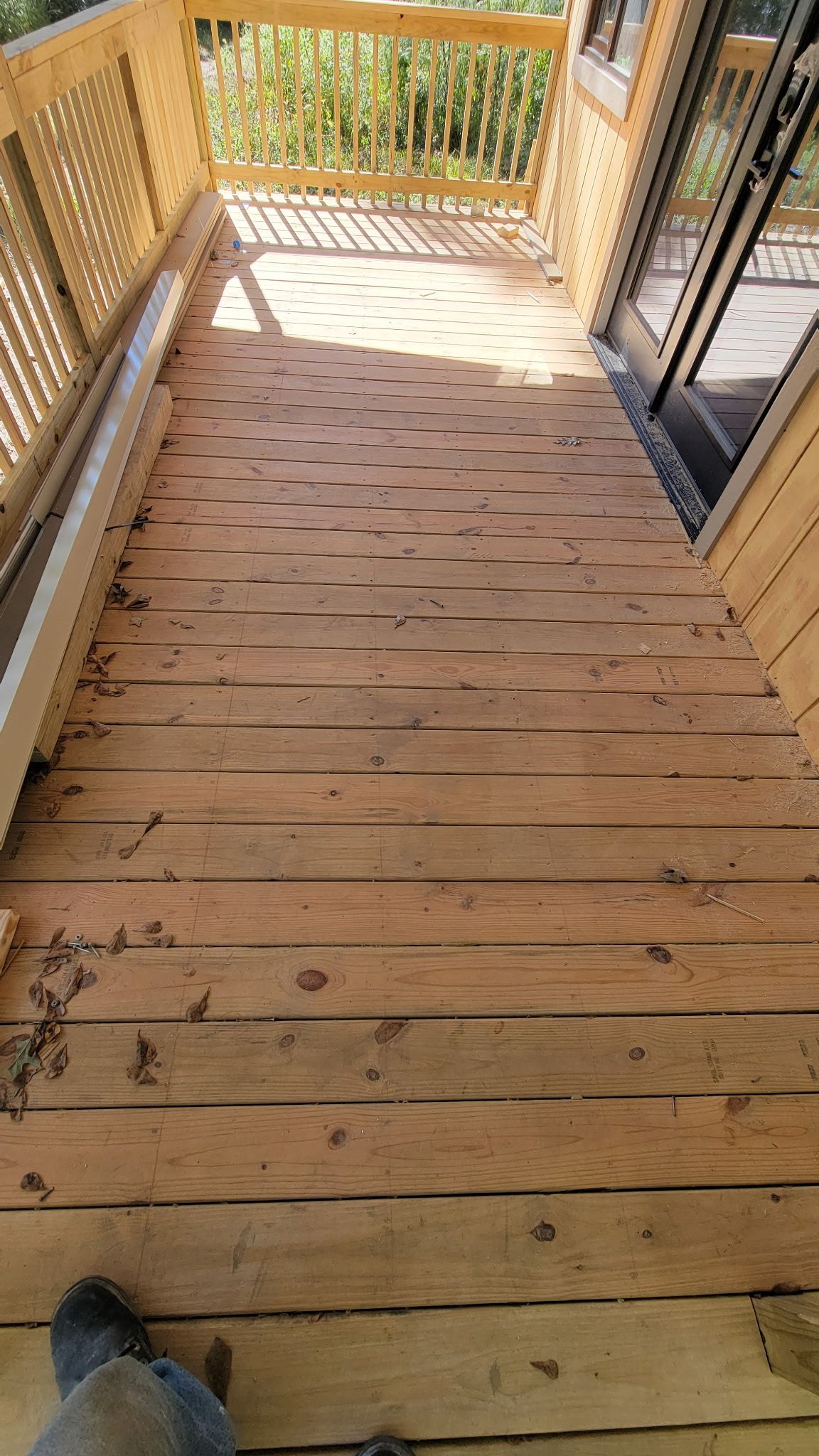 Wooden deck leading to a door, with railings and sunlight.
