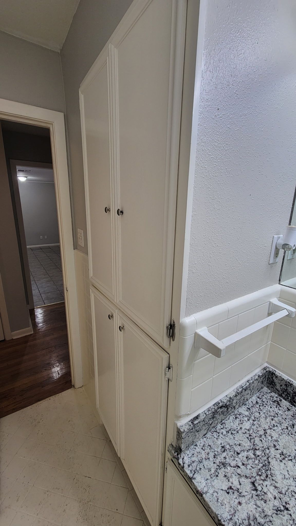 White kitchen cabinets and countertop next to a doorway. Light-colored flooring.
