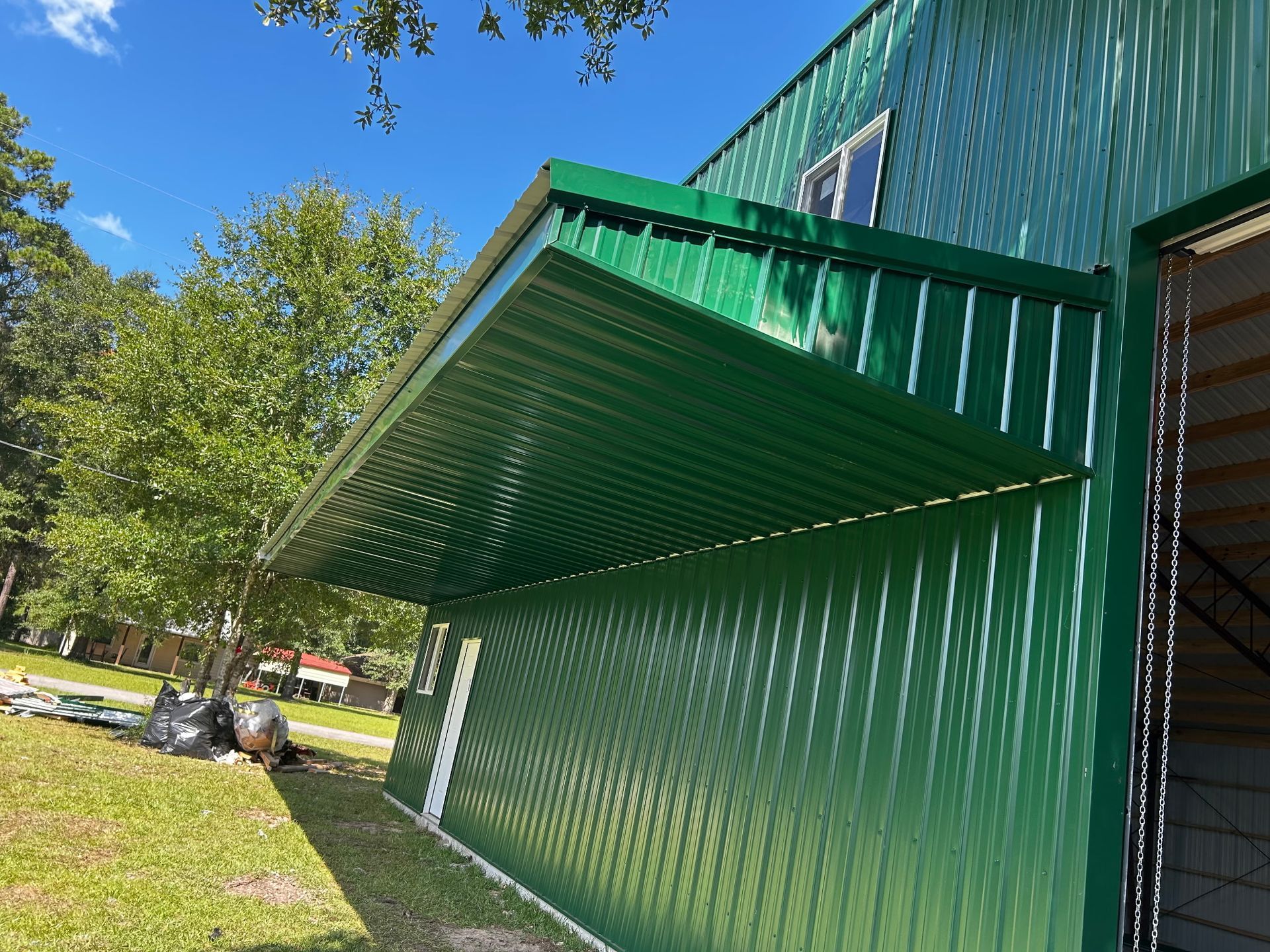 Green corrugated metal building with a matching awning extended on a sunny day.