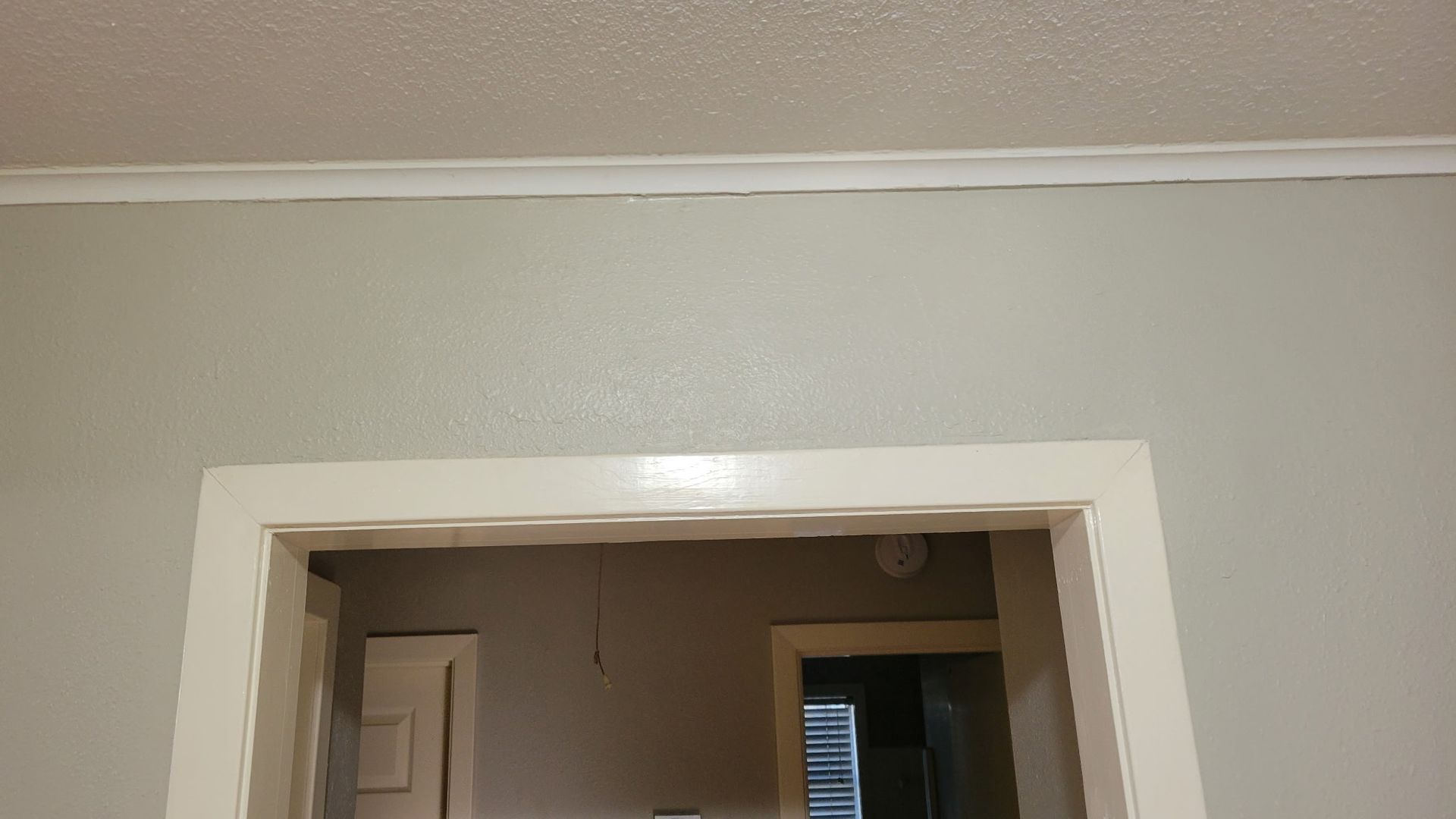 Light gray painted wall with white trim and doorway.