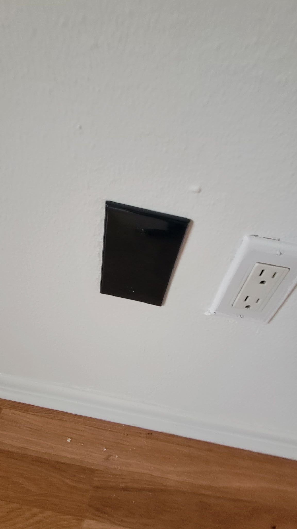 Black rectangular hole in white wall, adjacent to a white electrical outlet.