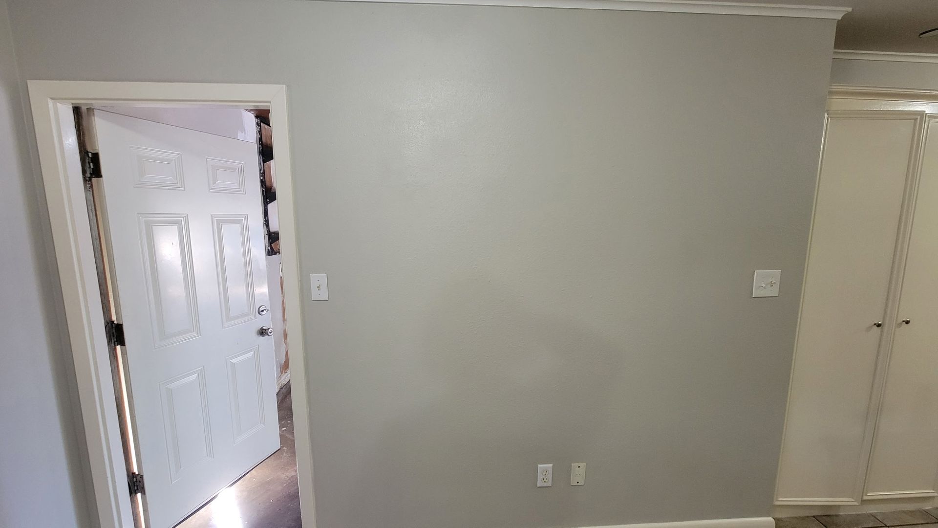 Interior view of a room with a gray wall, white door, and a white closet.